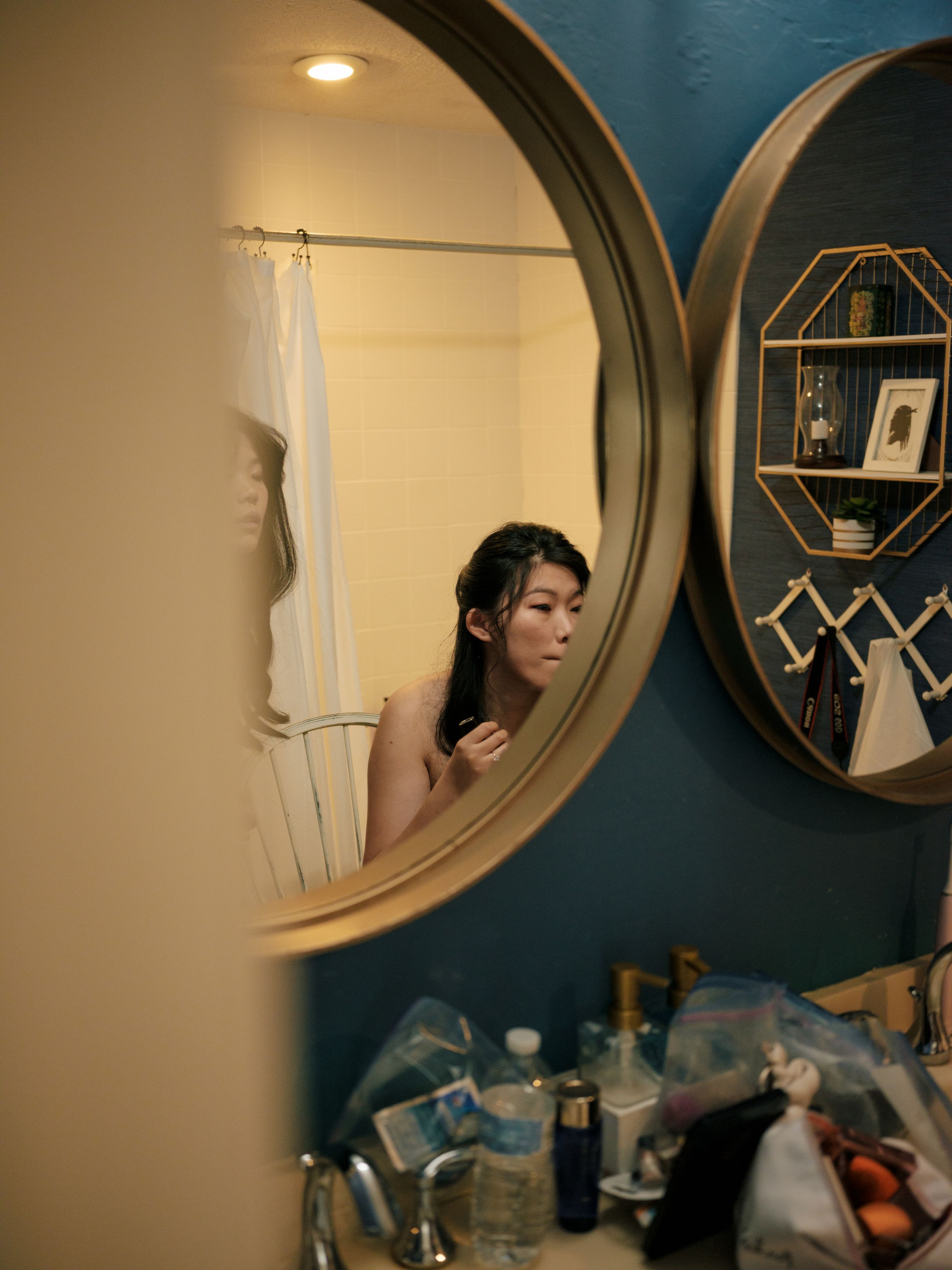 Series of mirror reflections in a dimly lit room with dark blue walls and vanity items.