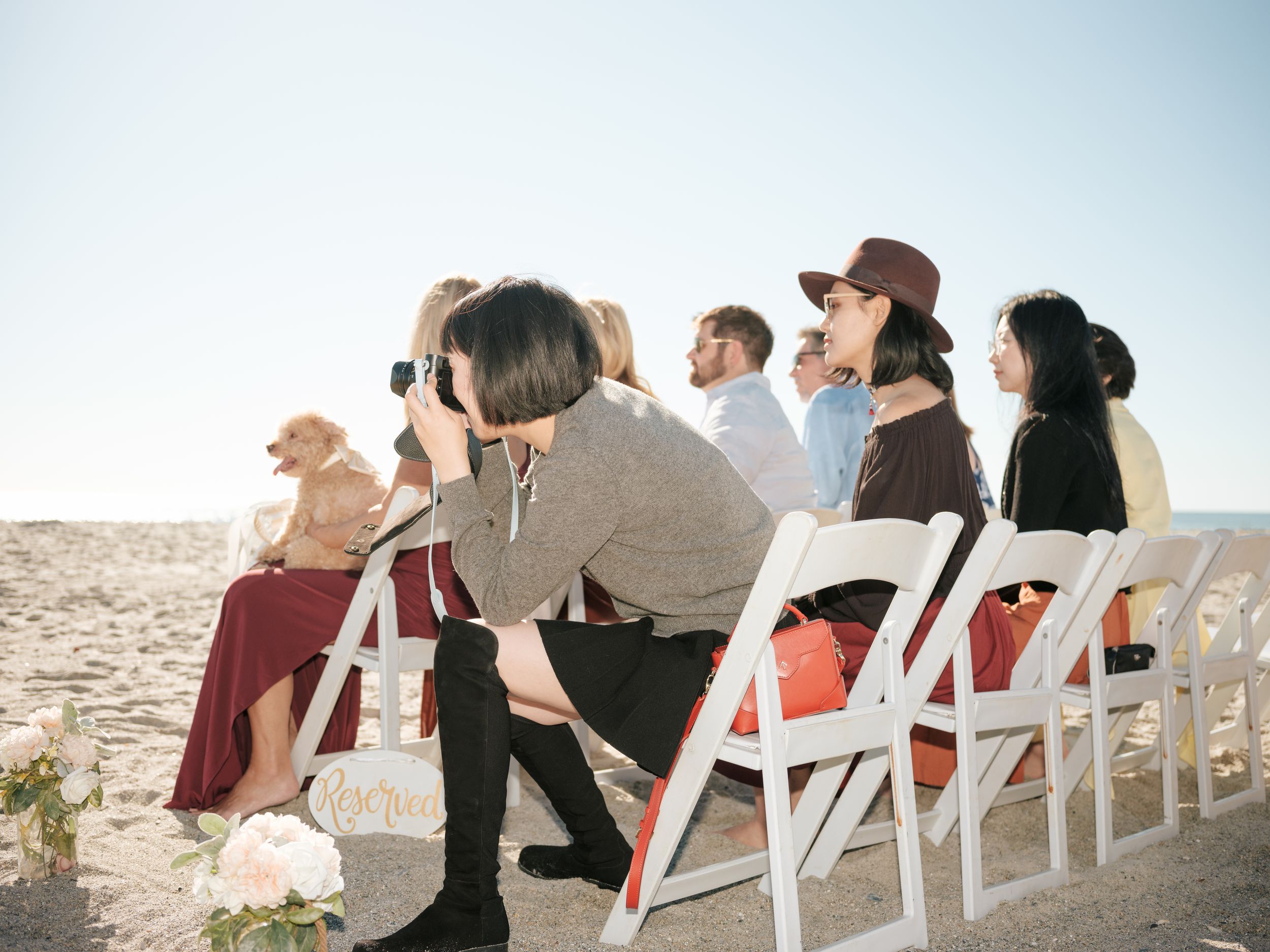 White folding chairs arranged in rows on a beach during an outdoor event.