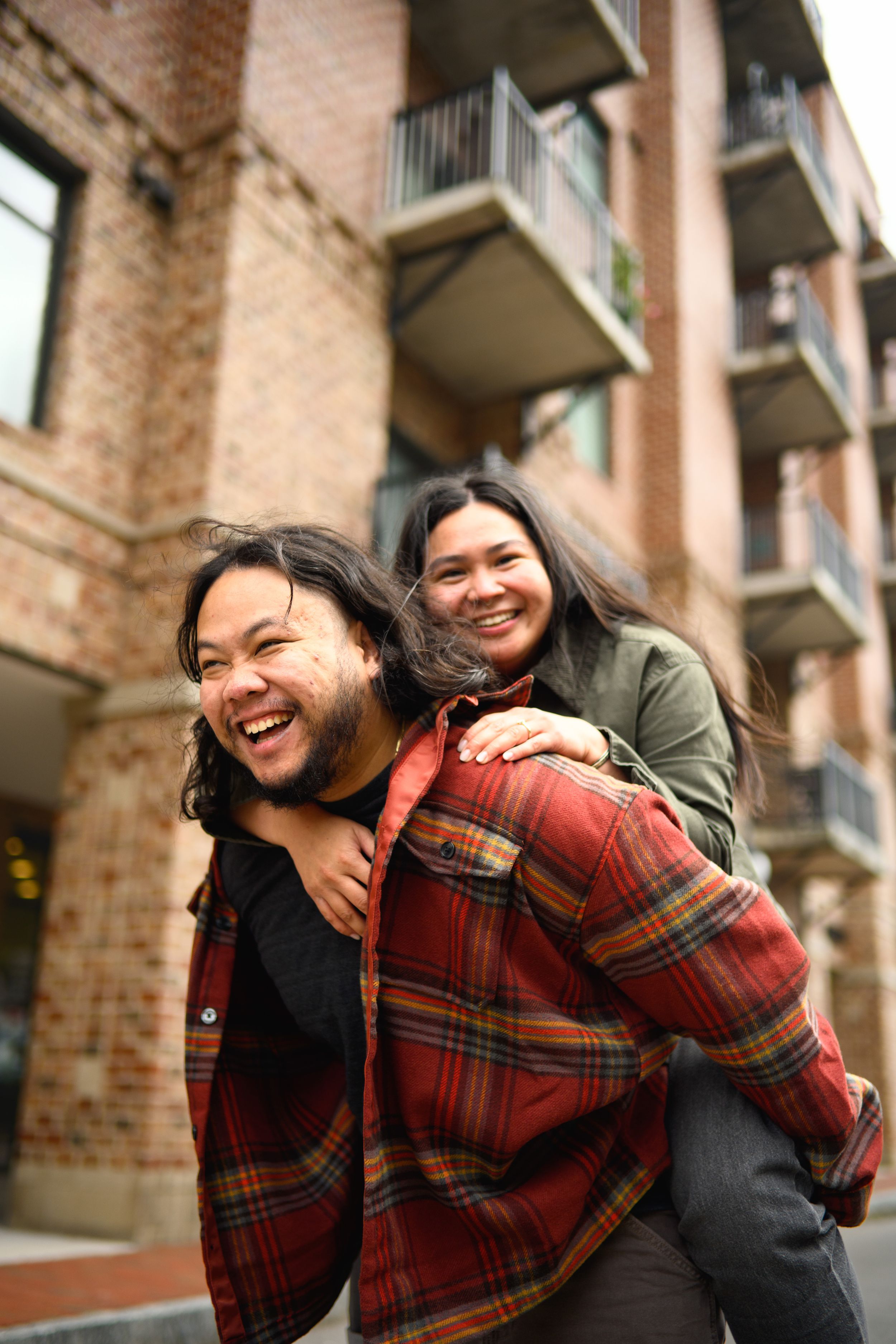 A series of candid moments showing a couple laughing and embracing outside a brick apartment building.
