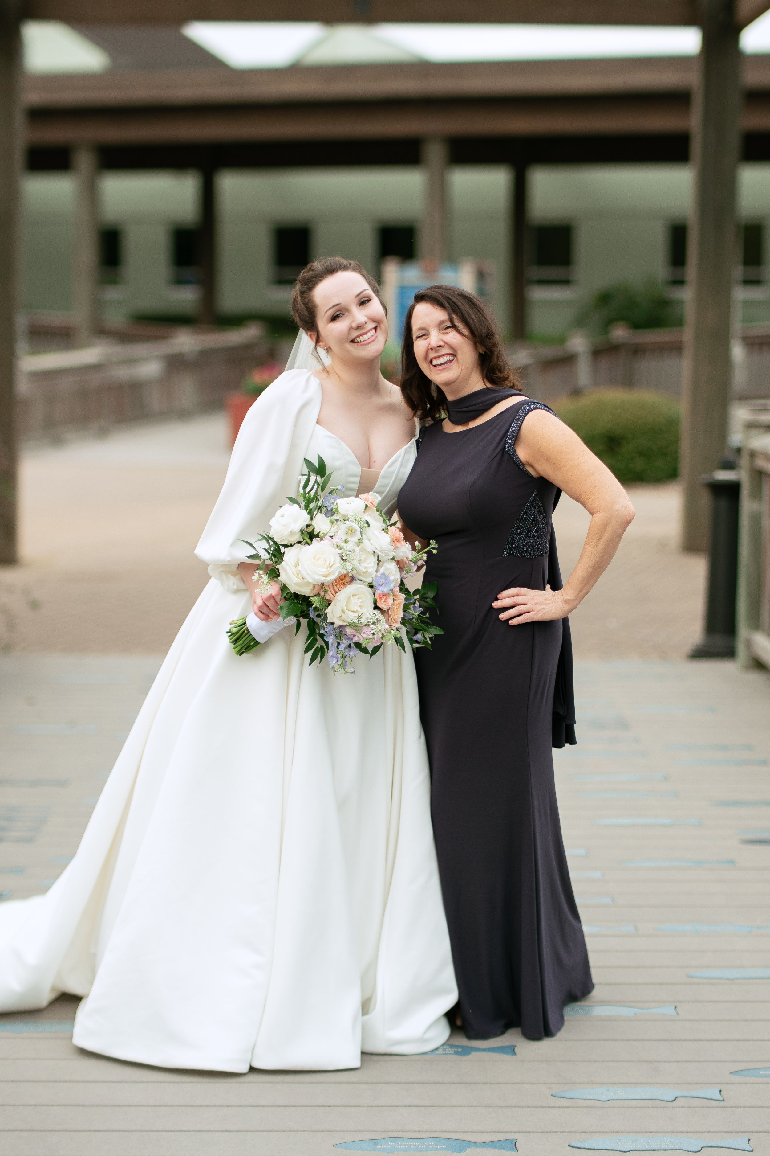 Two people in contrasting black and white formal attire stand together at an outdoor venue.
