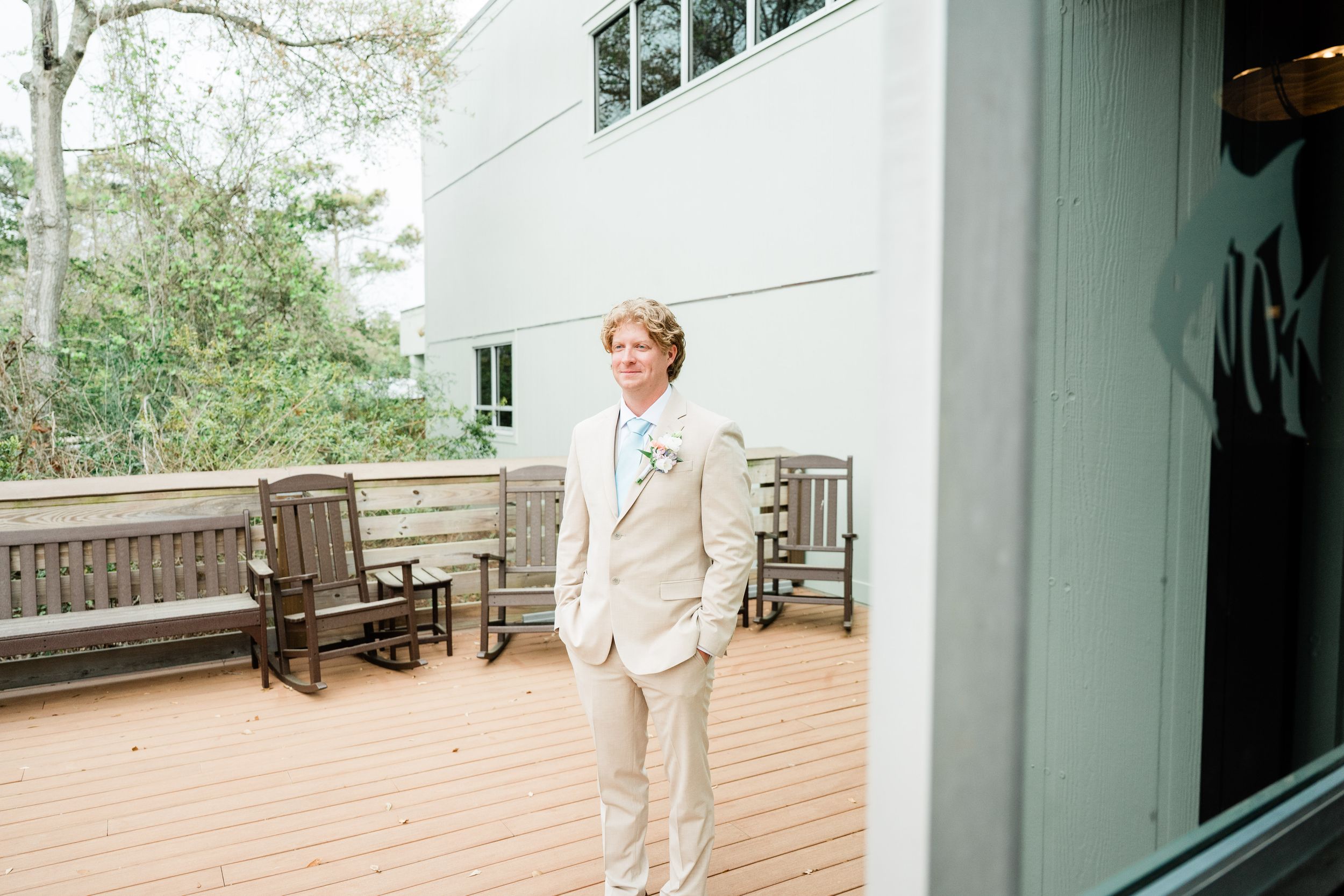 Modern white building exterior with wooden deck and benches for an outdoor wedding venue.