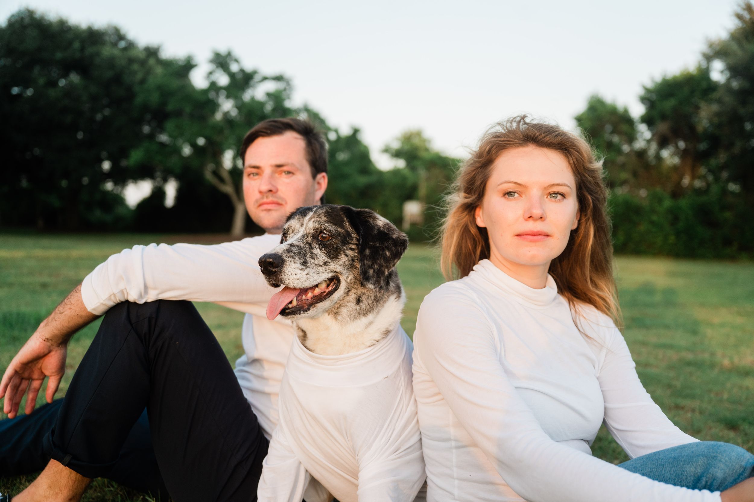 A person and their dog enjoying a sunny afternoon together in a grassy field during golden hour.