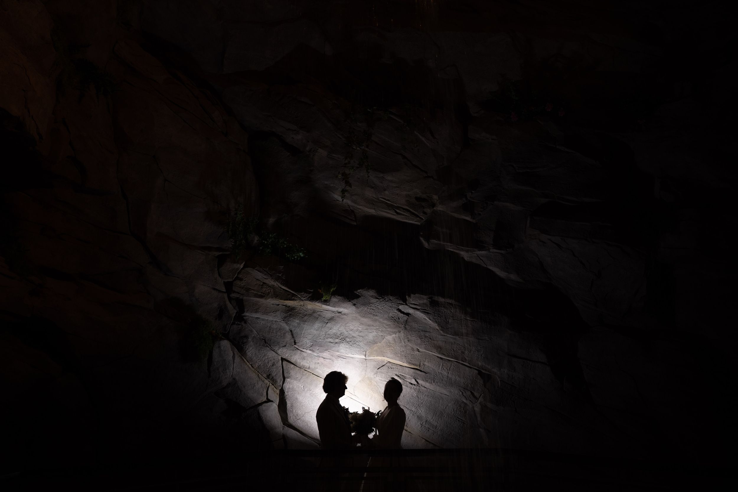 Dramatic silhouette of a couple against a lit cave wall creating a romantic atmosphere.