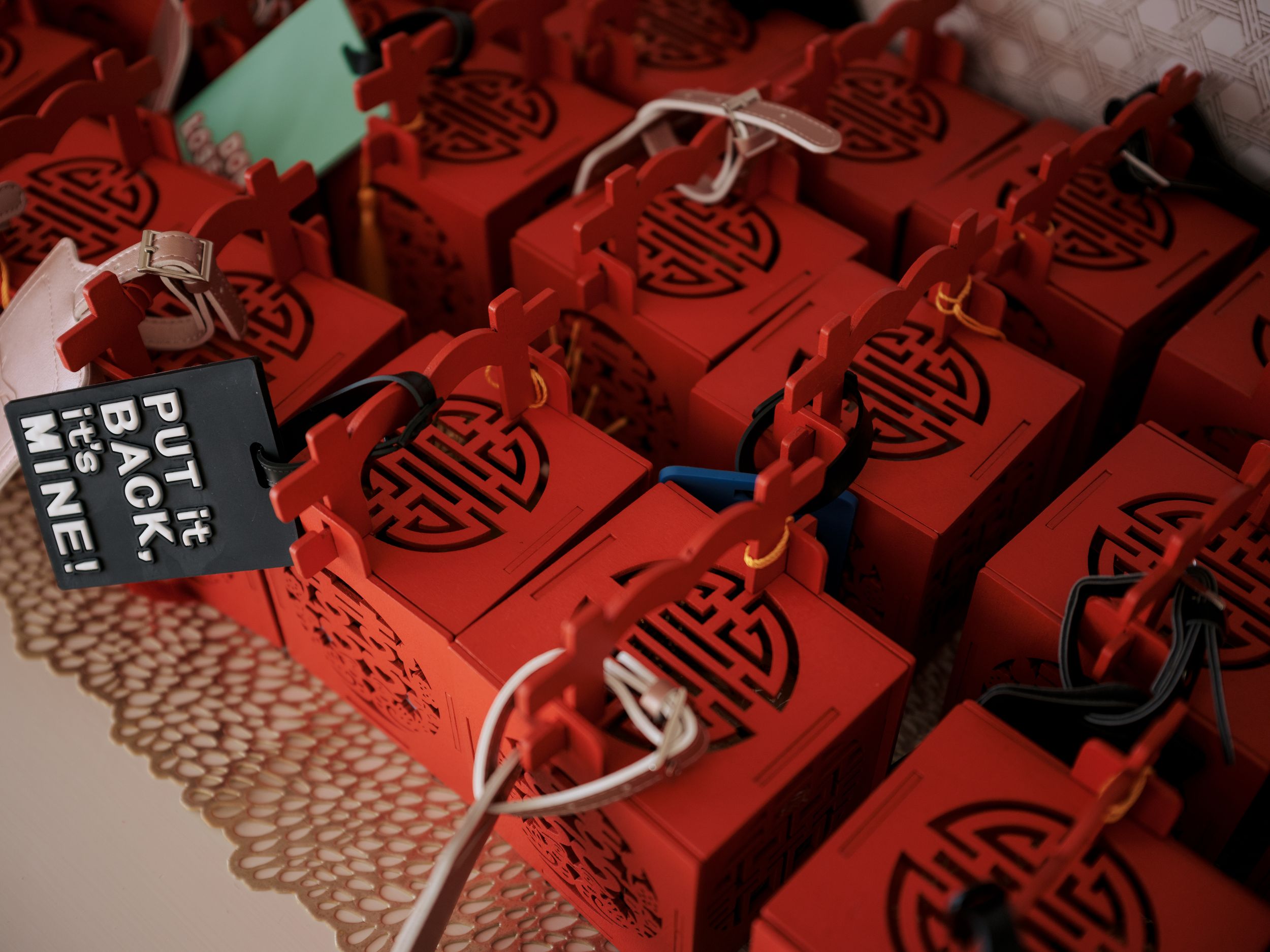 Several red cardboard takeout boxes with Chinese calligraphy designs sit on a patterned tablecloth surface.