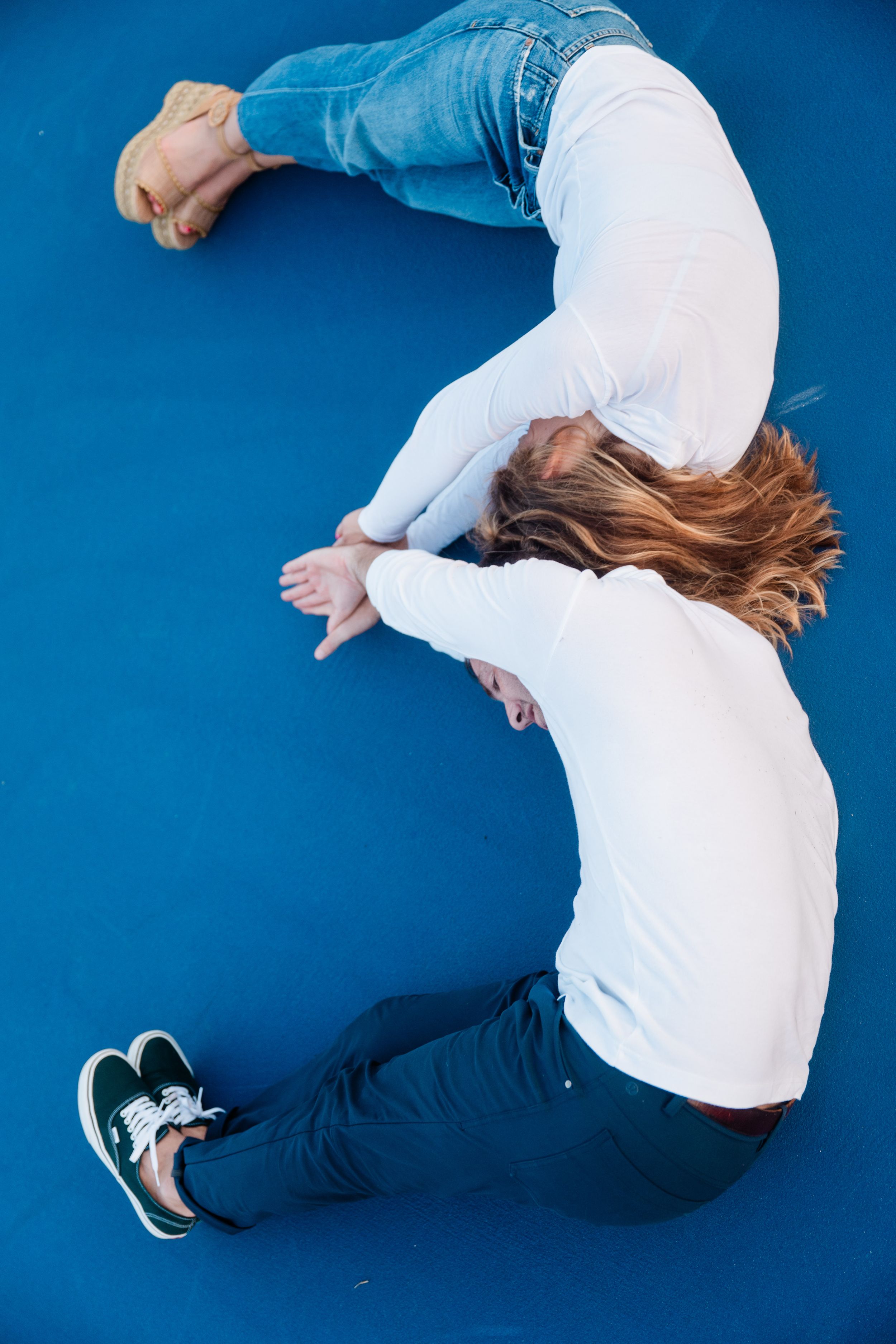 Sequence of someone rolling on a blue surface wearing white top and jeans.