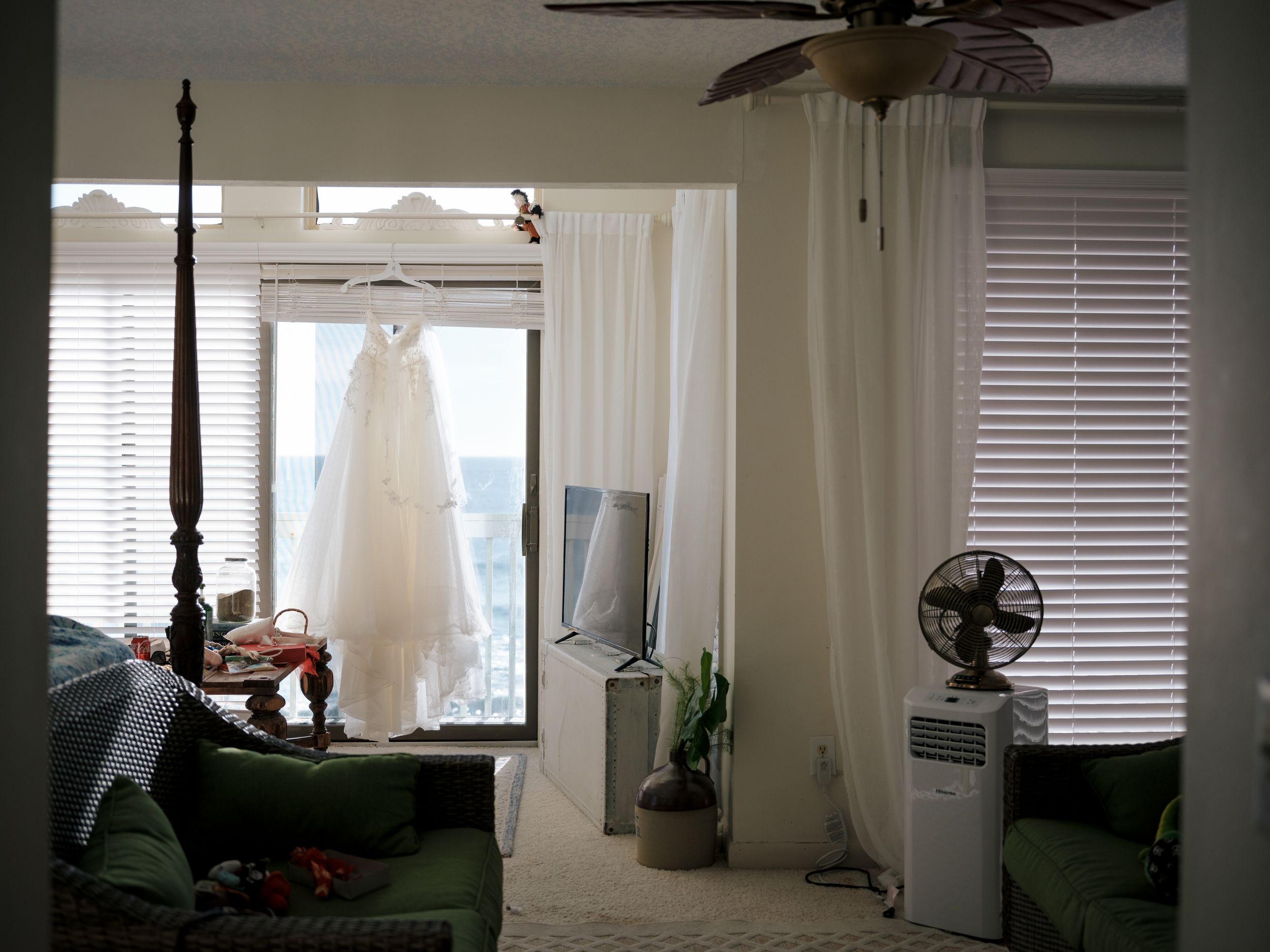 Interior room with sunlight streaming through white curtains and windows showing coastal views.