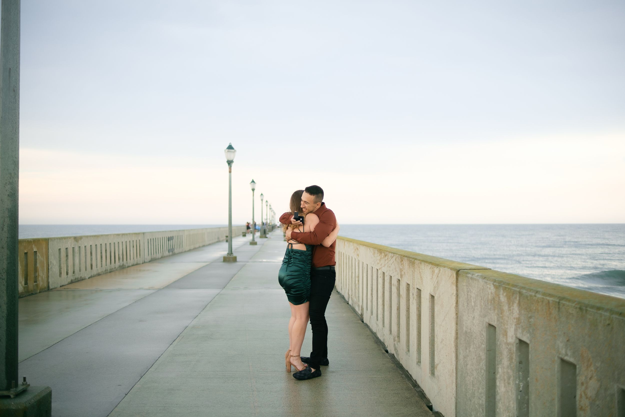 A couple shares romantic moments on a beachside pier during sunset.