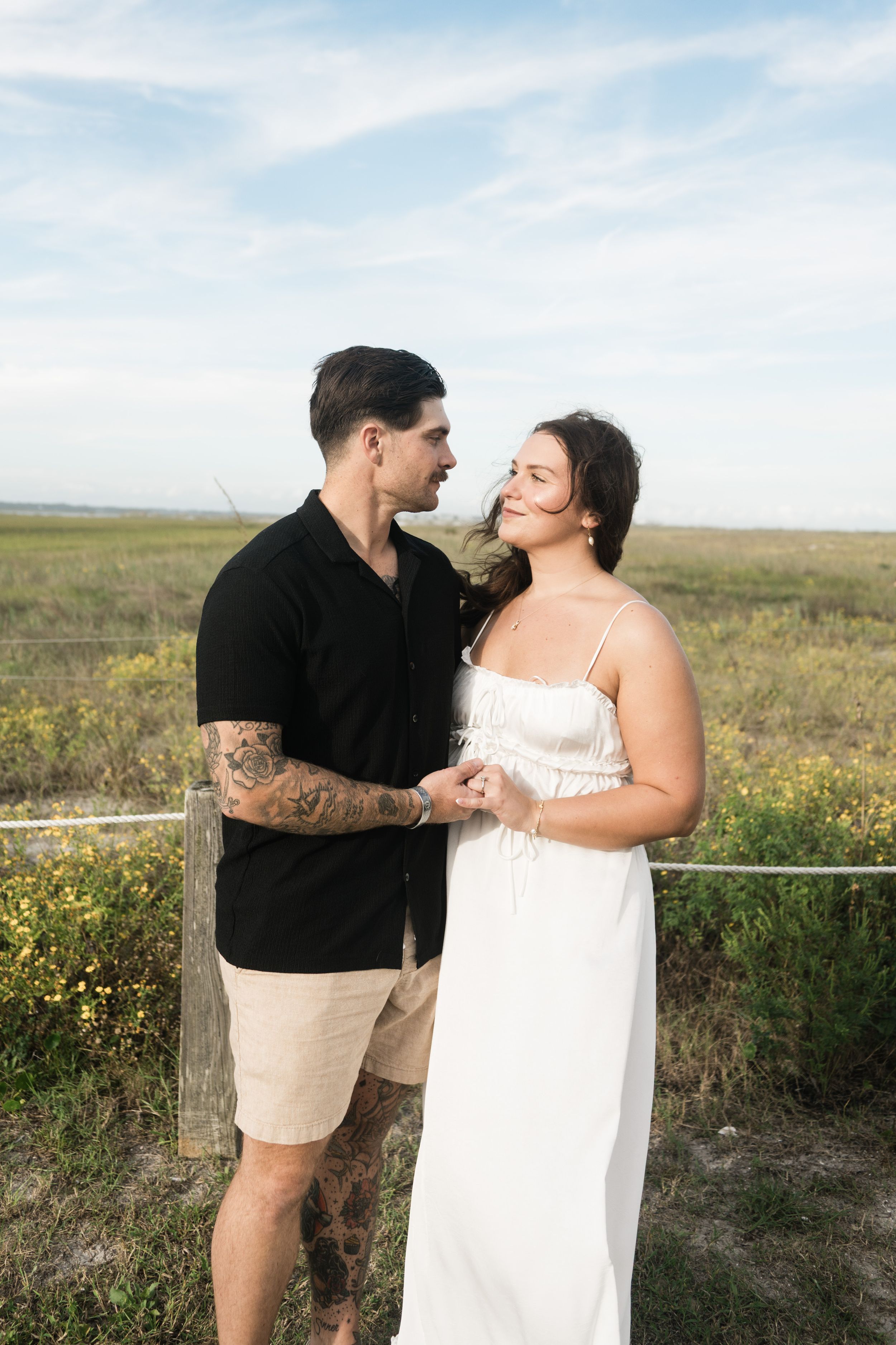 A couple shares romantic moments together in a field of yellow wildflowers at sunset.