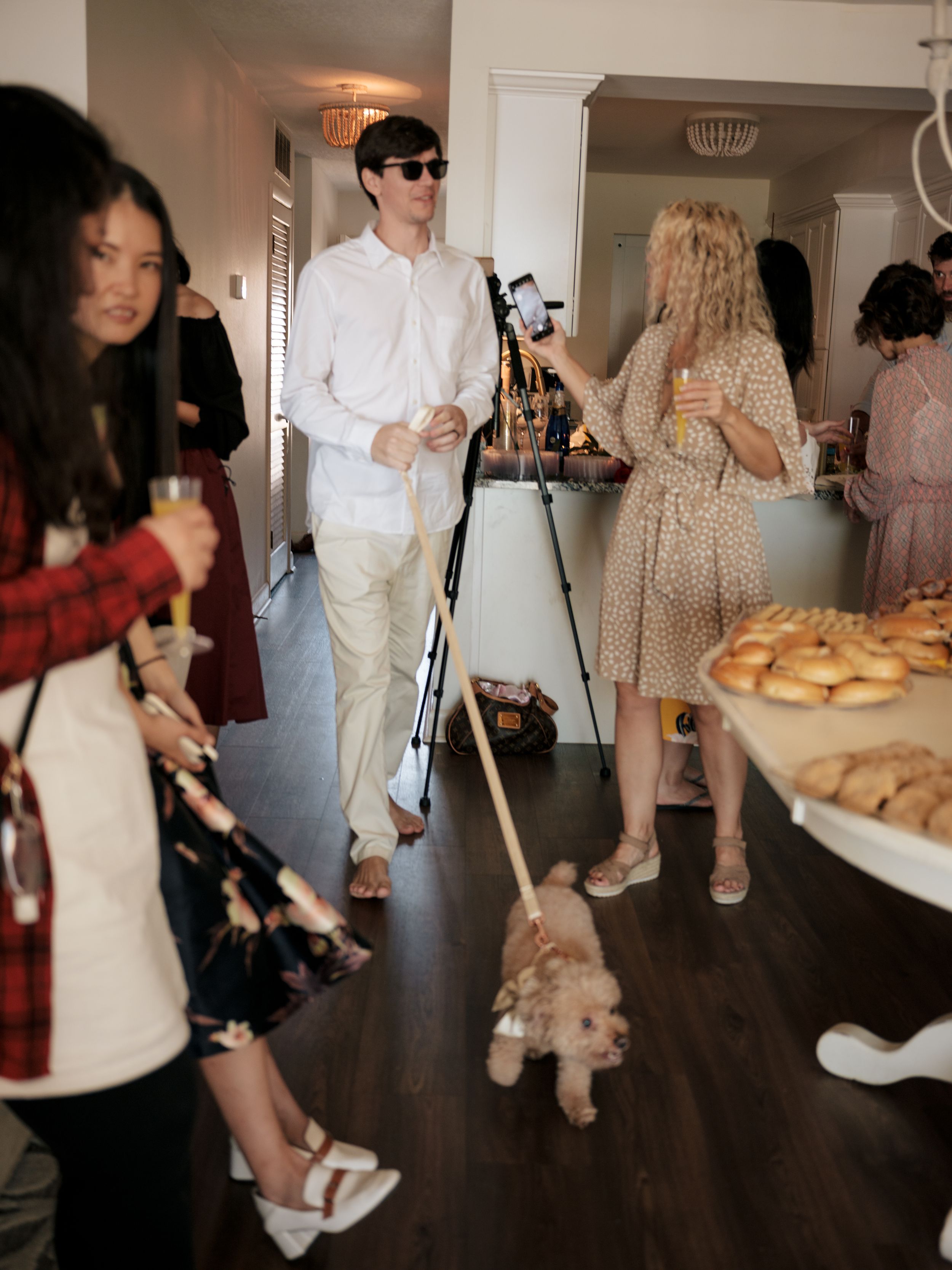 People gathering at an indoor party with refreshments and food served on tables.