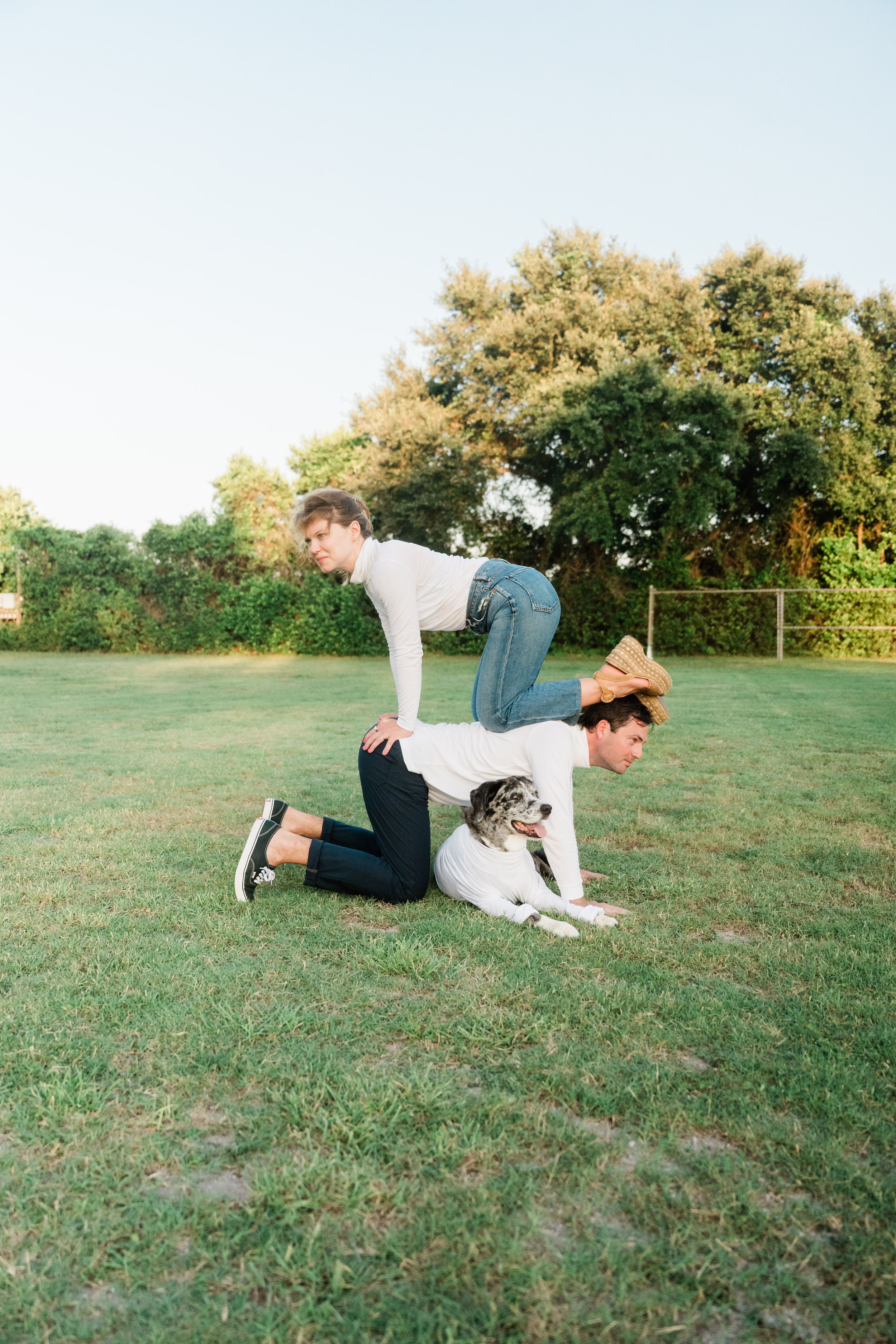A person lies on grassy ground playing with a small dog while enjoying an outdoor afternoon.