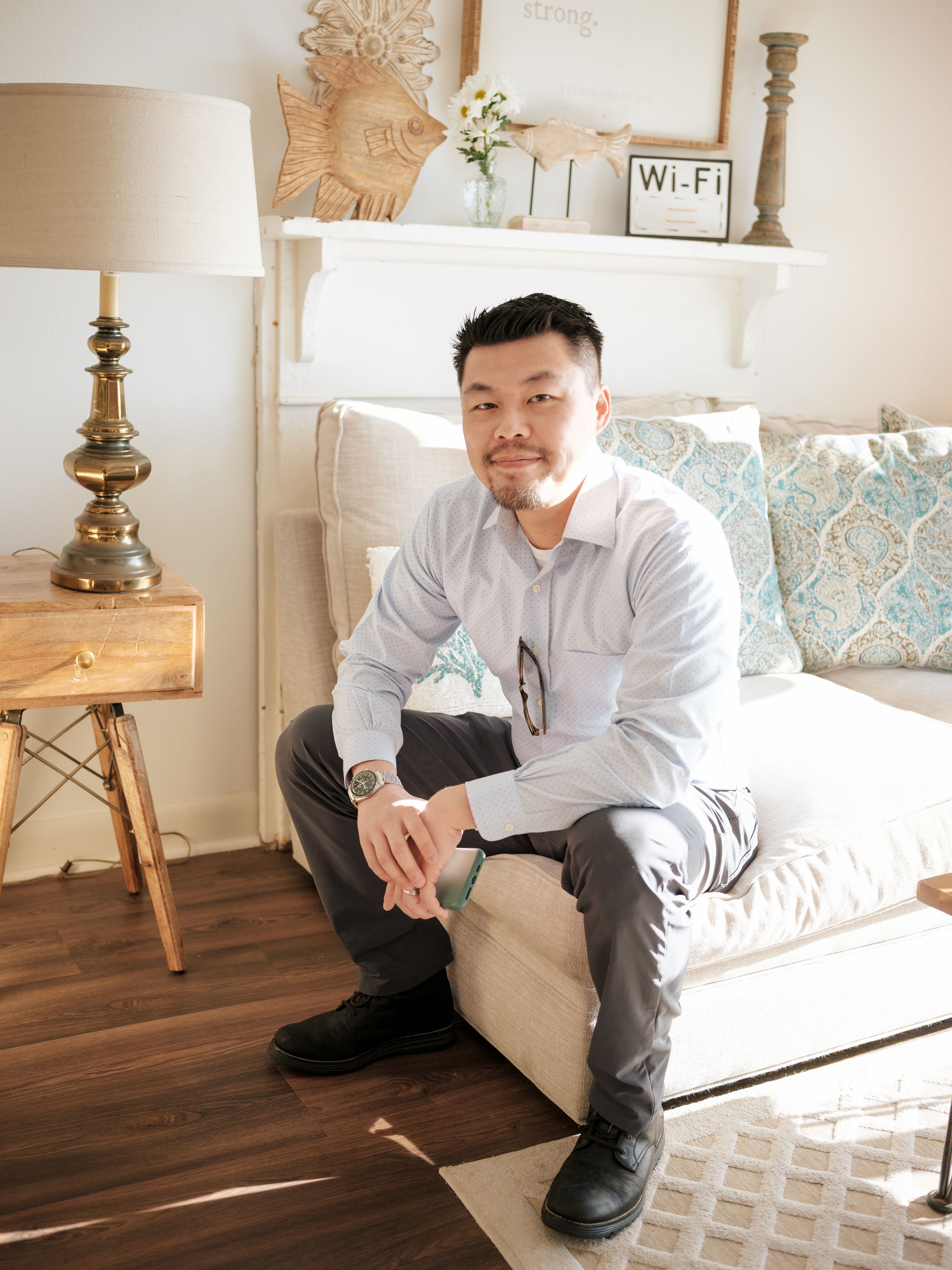 Person relaxing on a white couch in a cozy living room with decorative pillows and wooden floors.