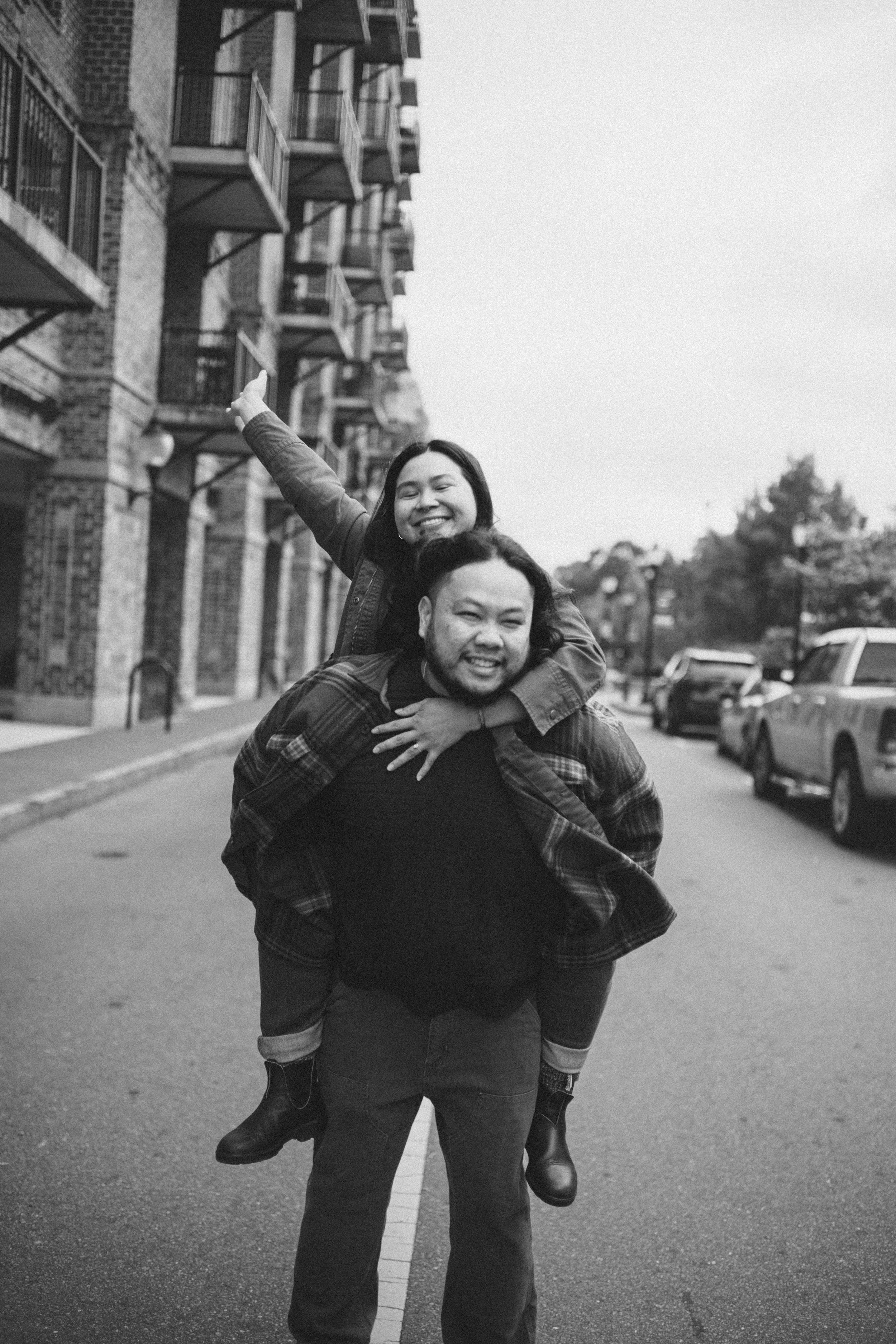 Black and white photo series showing a playful piggyback ride moment on an urban street.