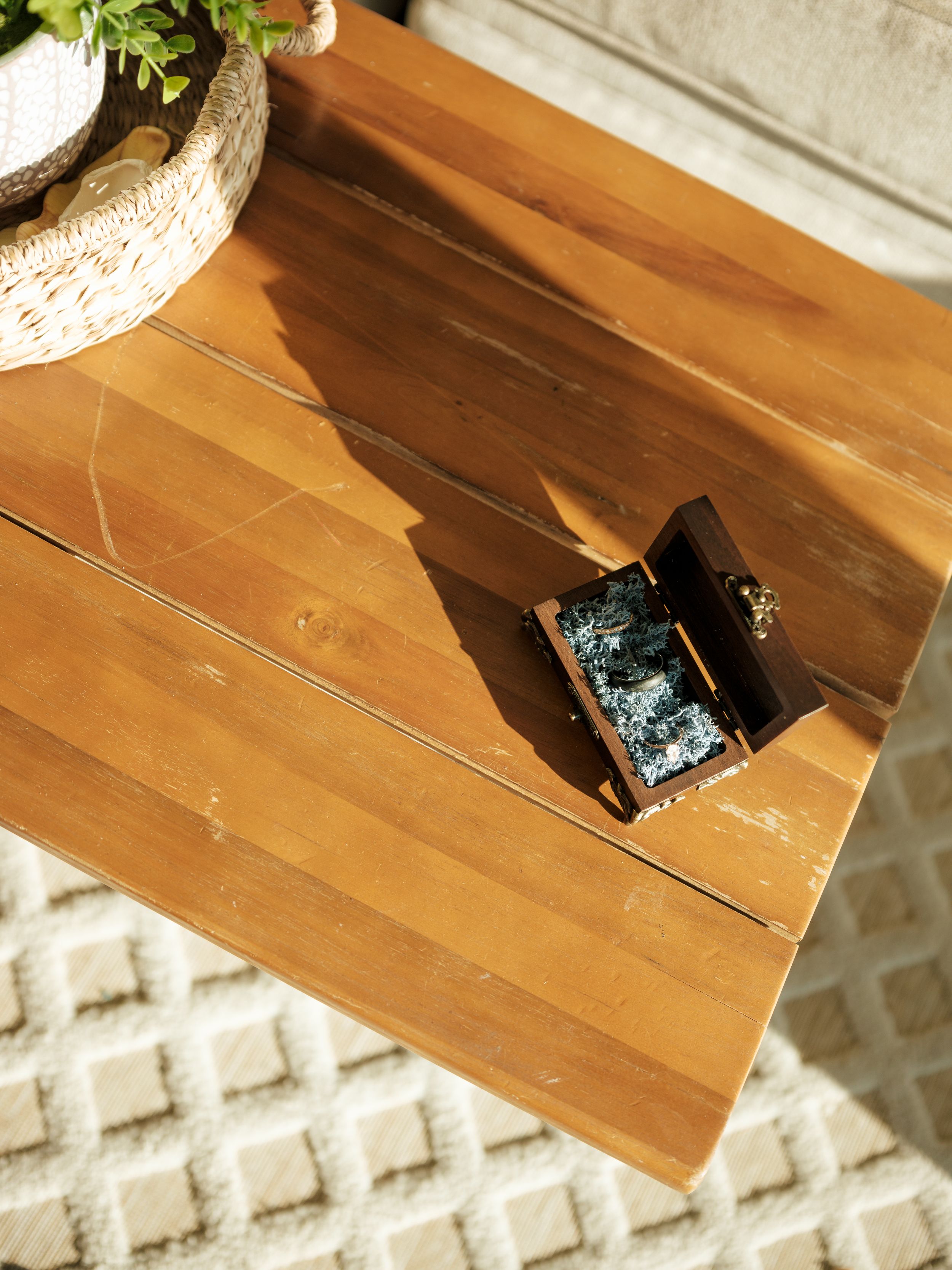 A wooden table surface with a small electronic device and decorative plant pot in natural lighting.