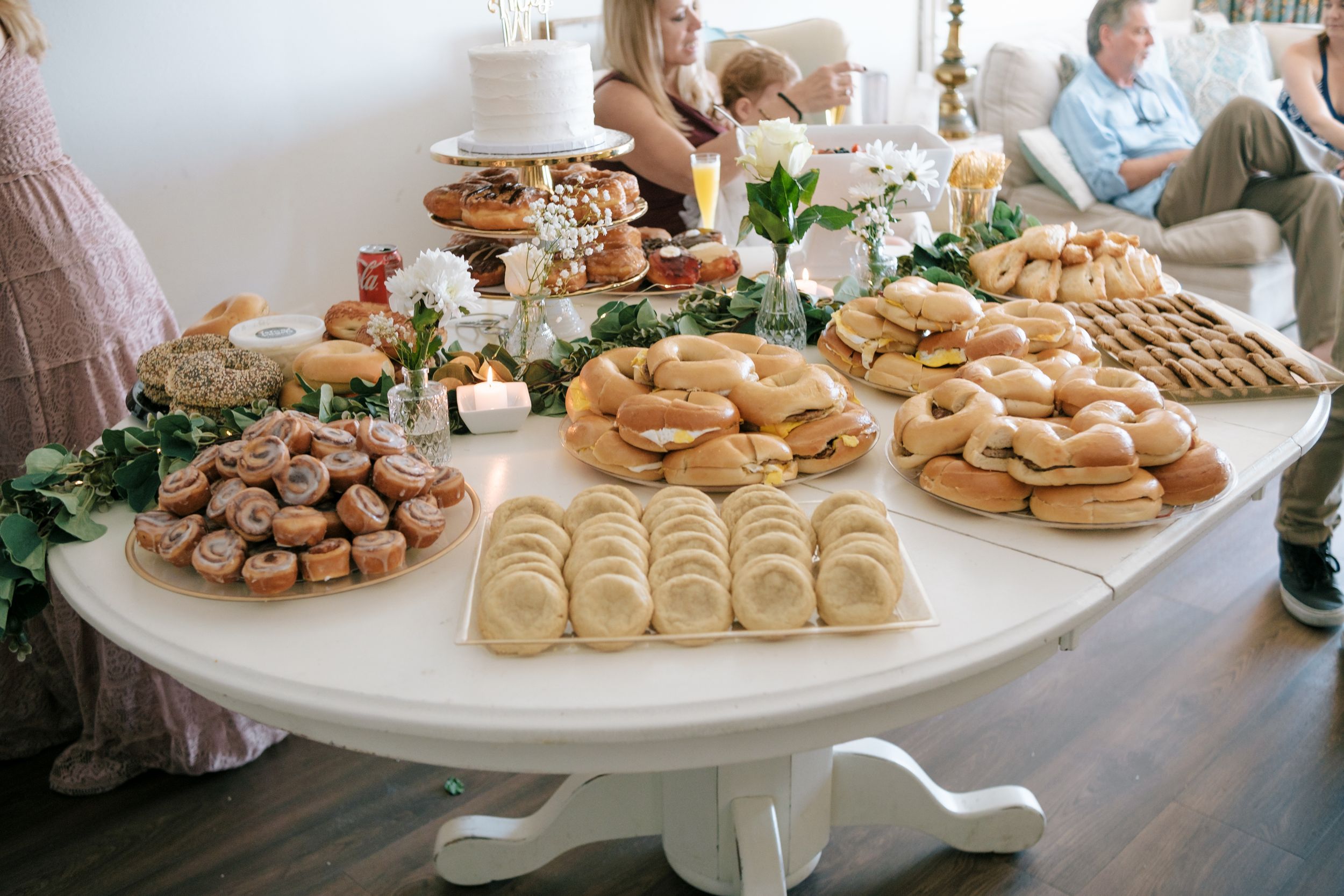 White dessert tables displaying an array of elegantly arranged pastries and treats at a catered event.