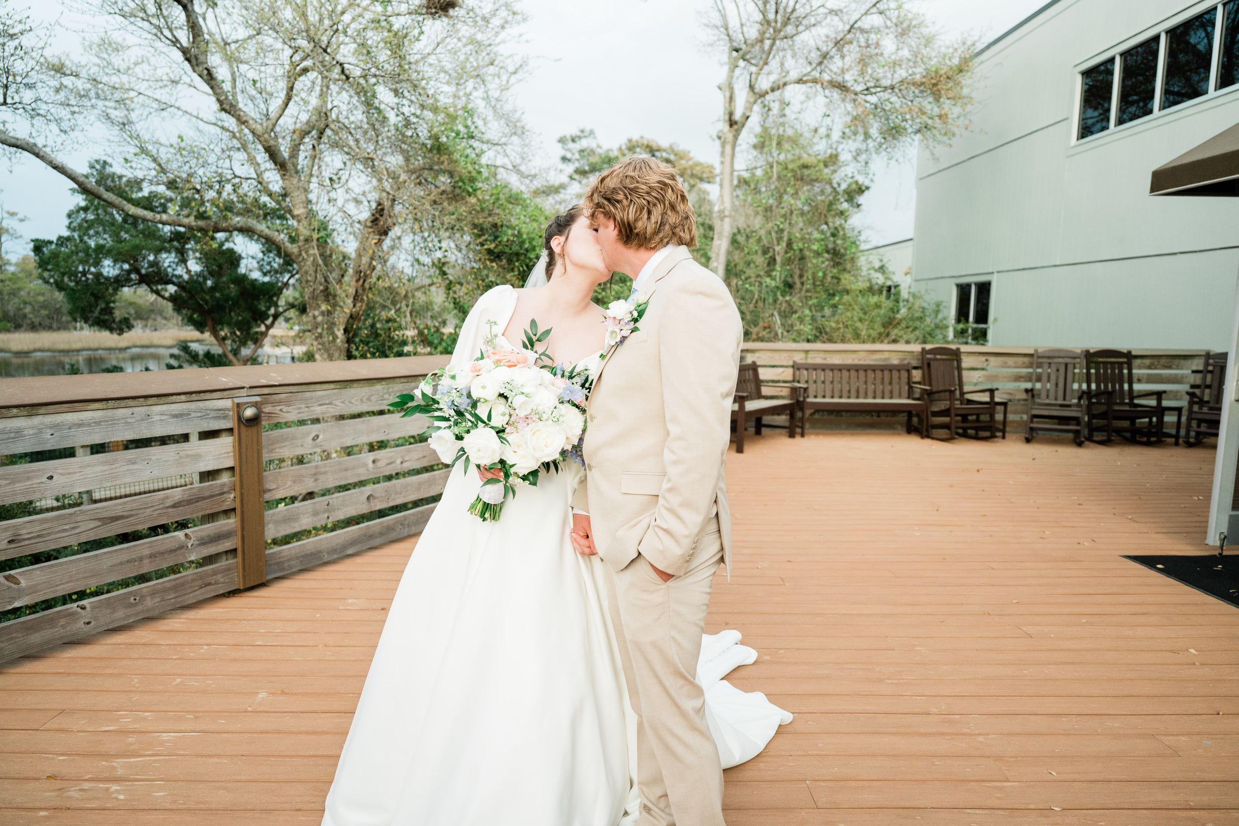 Wedding celebration on an outdoor wooden deck with scenic natural surroundings.