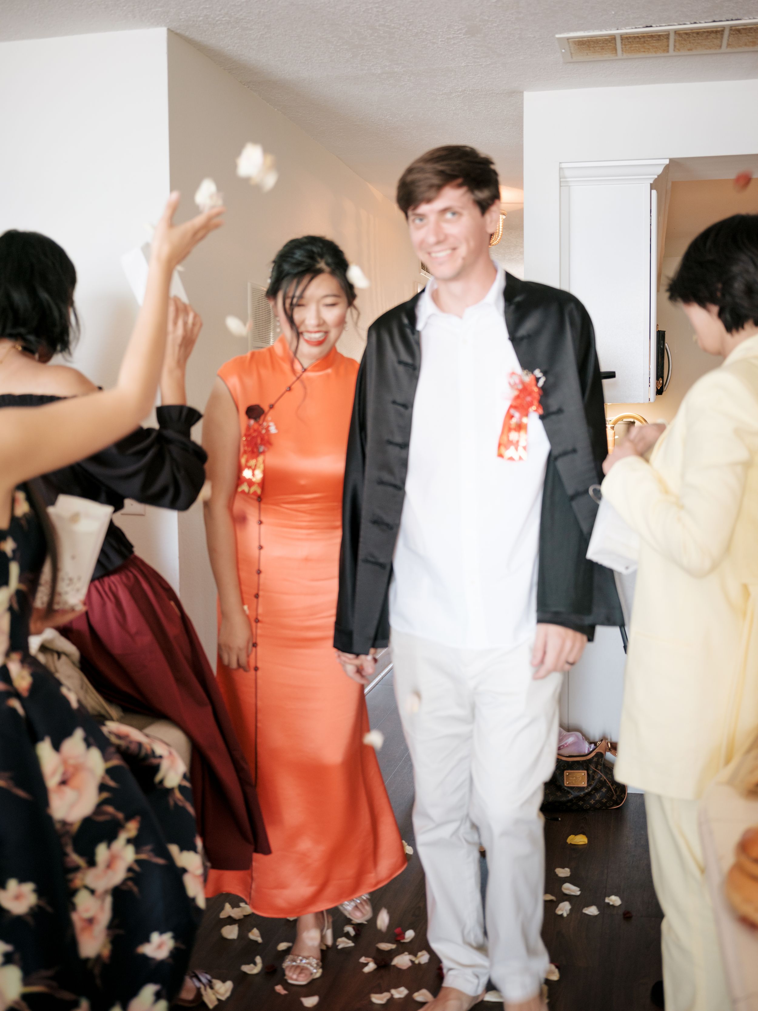 Wedding party celebrating with confetti and dancing in white indoor venue with joyful atmosphere.