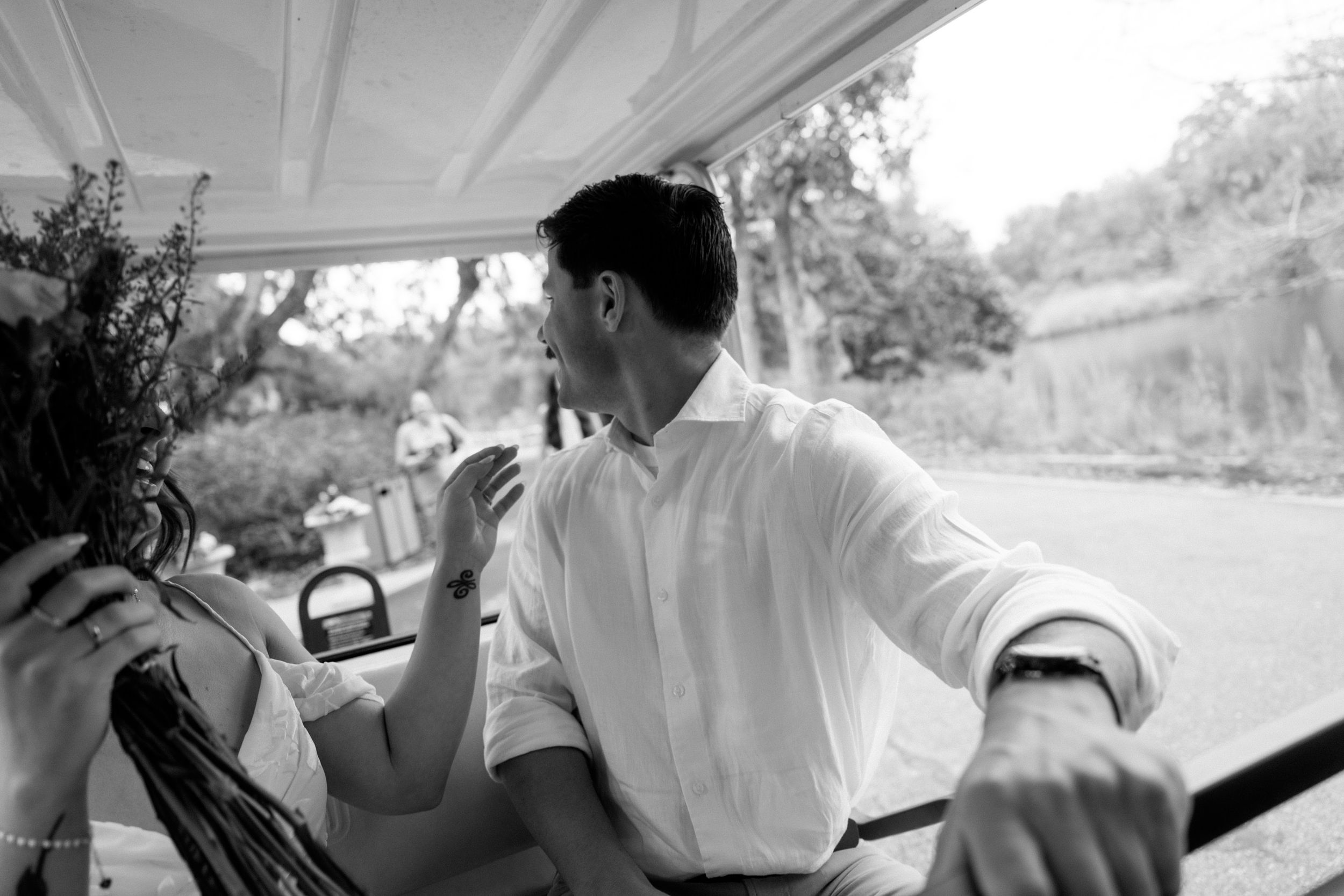 A person in a white shirt sits in a vehicle looking back over their shoulder in a black and white photograph.
