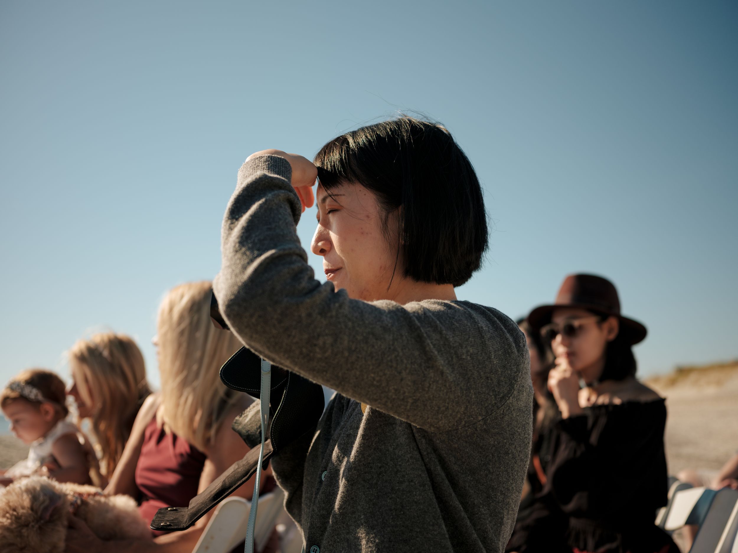 Wedding guests watching emotional ceremony moments on beach.