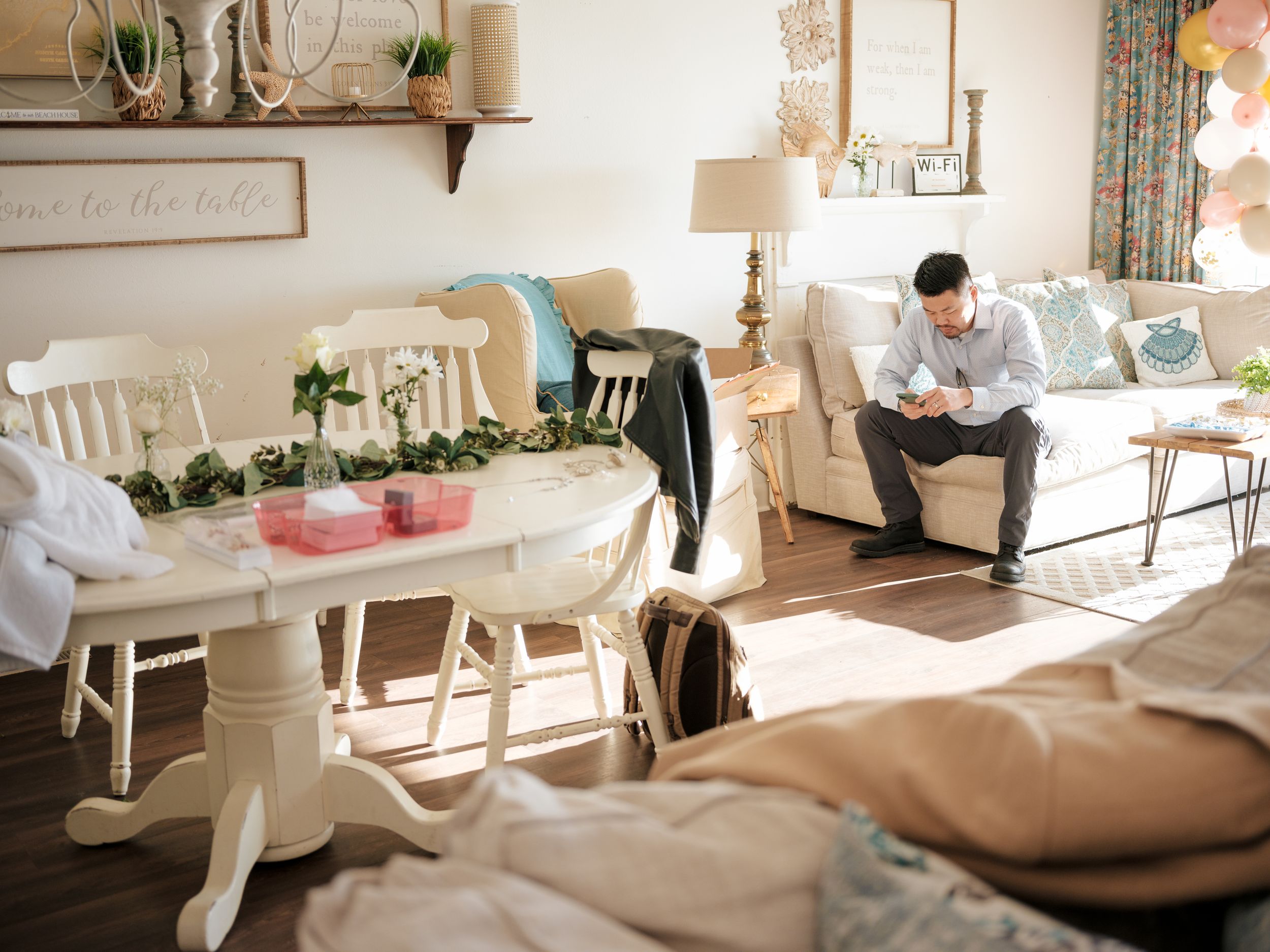 White dining area with rocking chair, table, and houseplants features a cozy farmhouse aesthetic design.