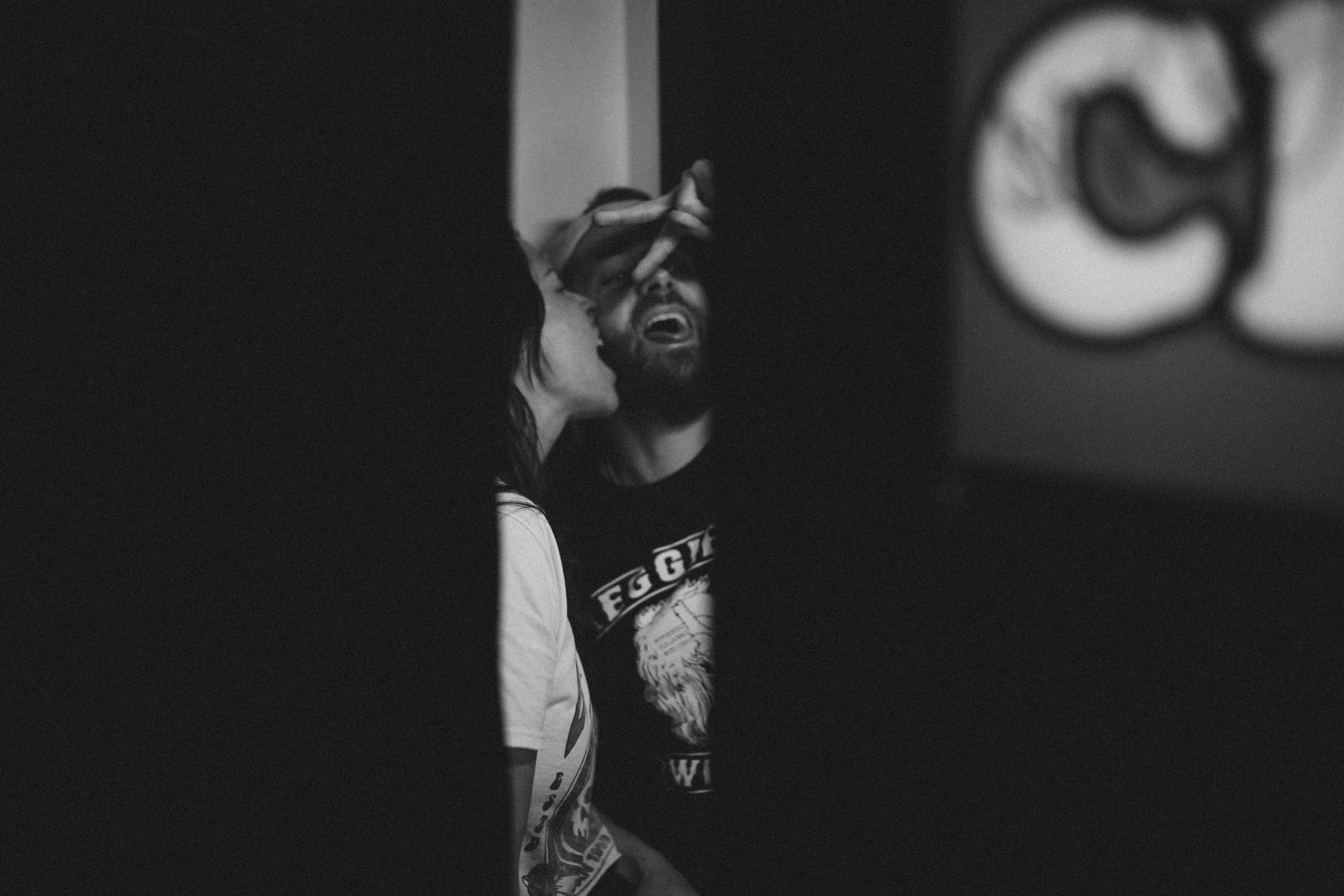 Dramatic black and white portrait of a person wearing a cap in low light.