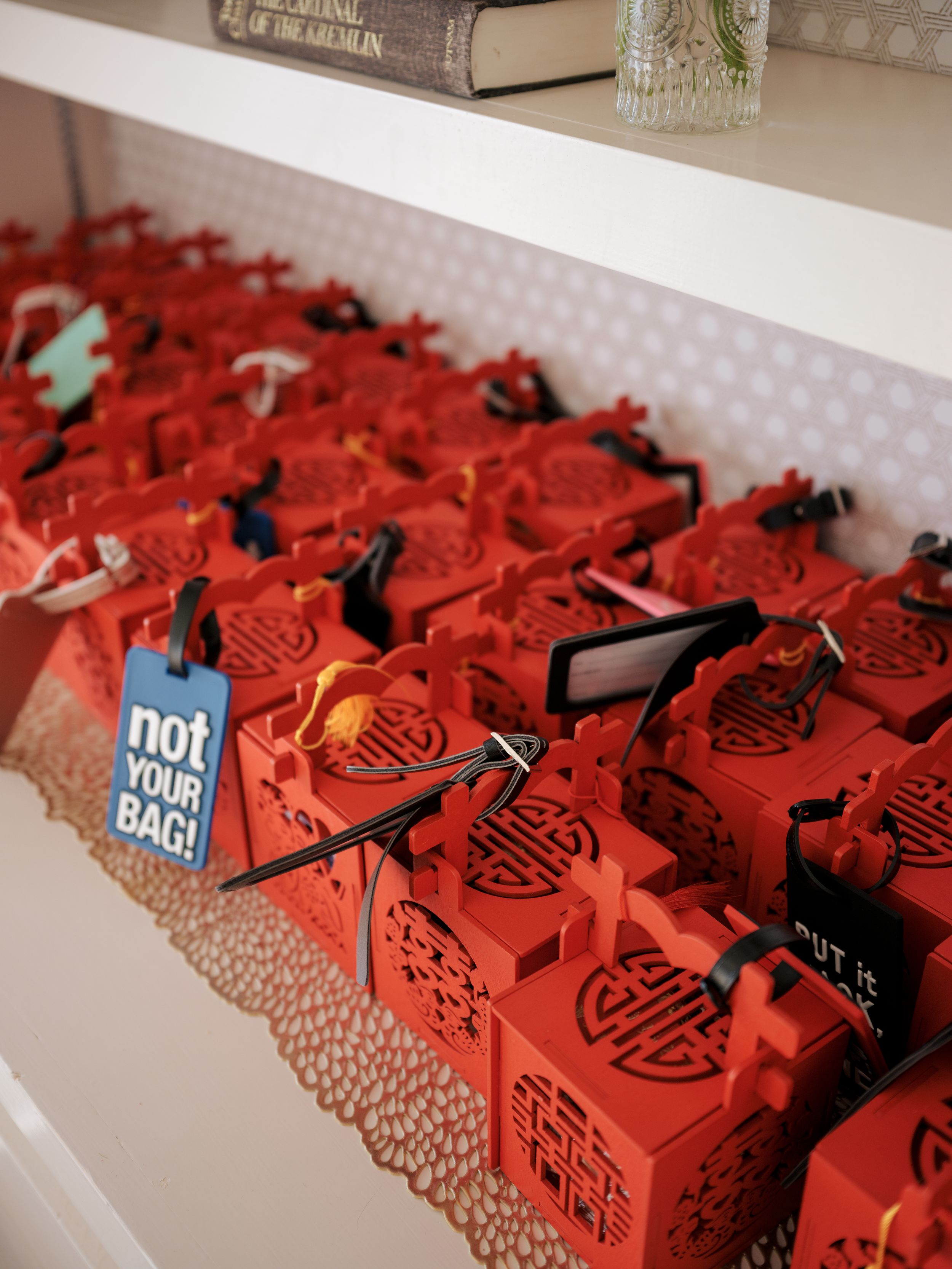 Rows of red favor boxes with tags arranged on a white shelf display.