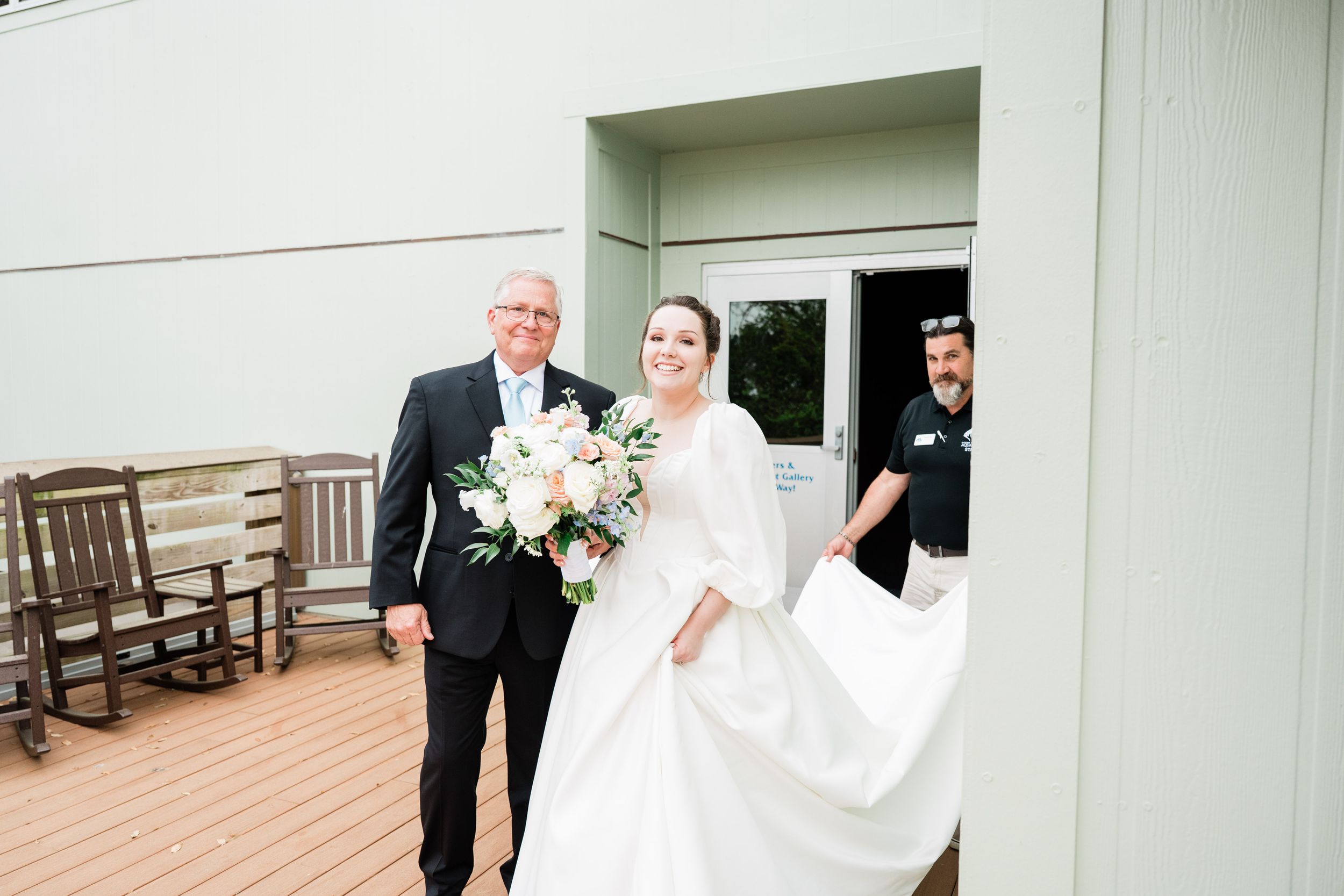 Wedding party members exit building onto outdoor wooden deck.