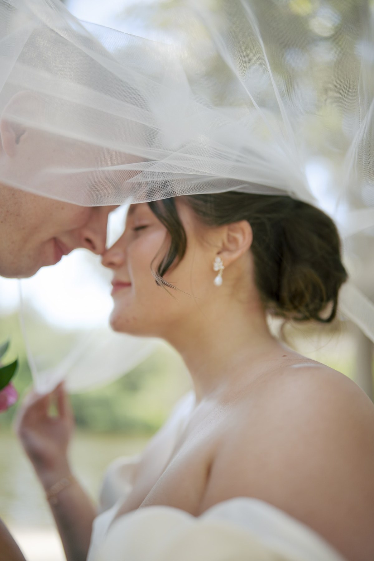 Lizzy and her partner sharing a close moment beneath her veil