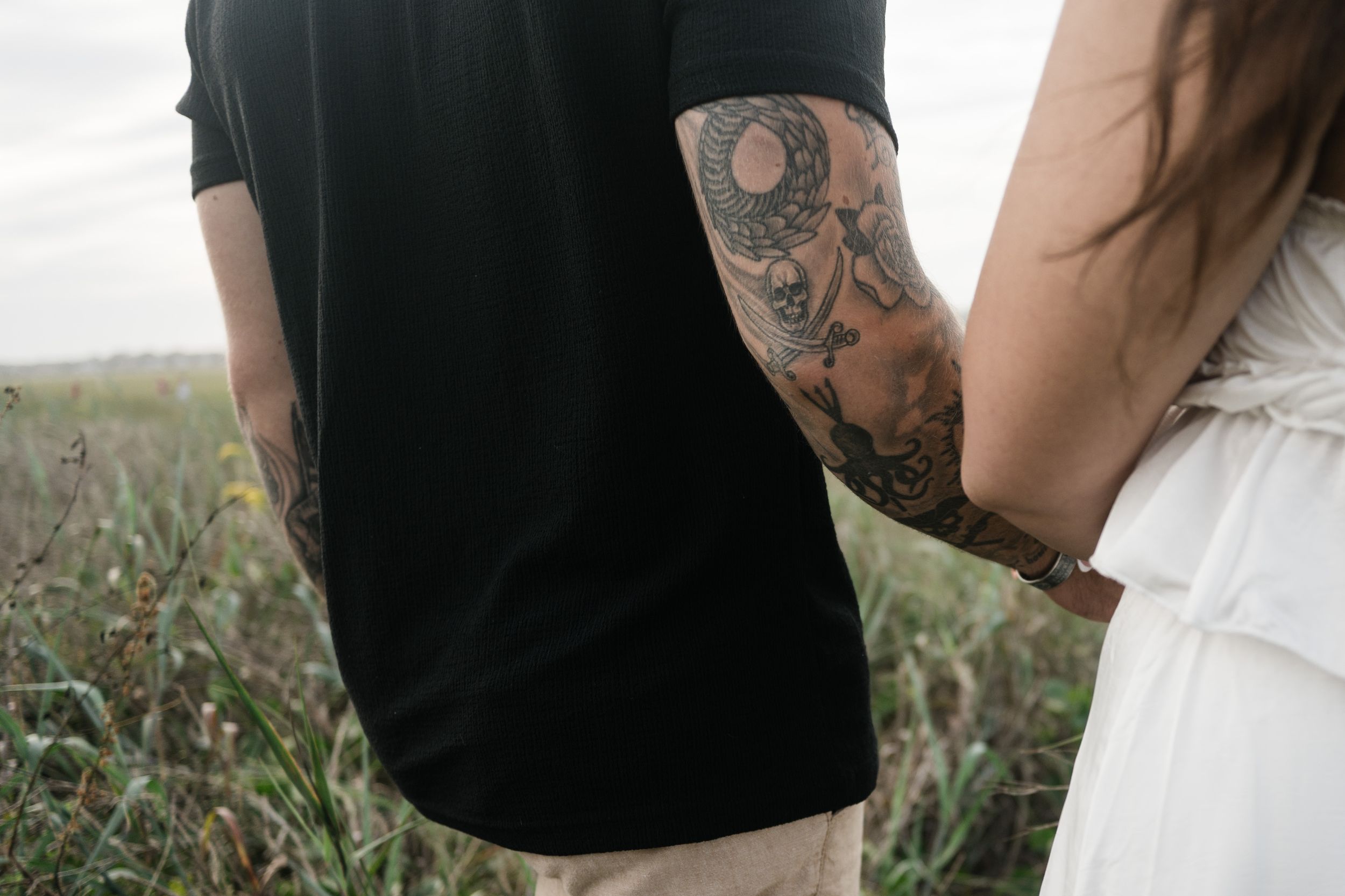 A couple shares a tender moment in a rustic field with tall grass and soft natural lighting.