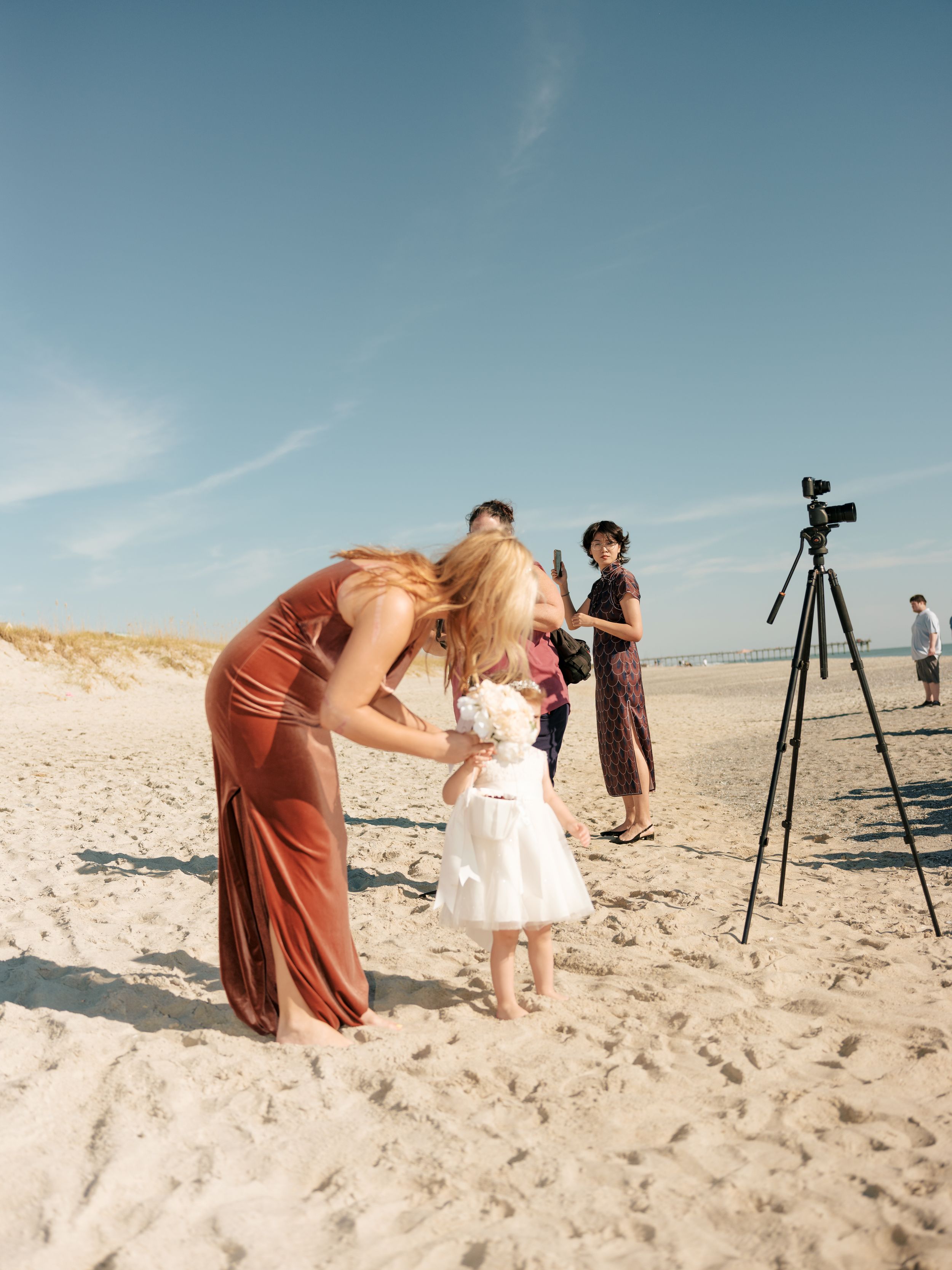 People with photography equipment set up on a sunny beach with tripods and cameras.