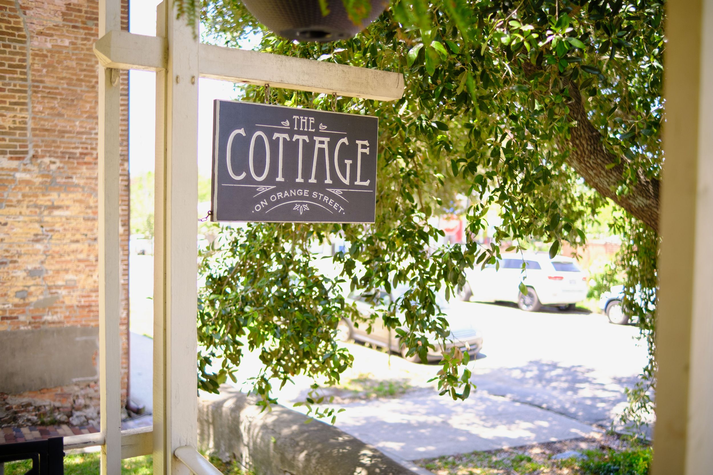 Rustic stone cottage exterior features an archway entrance and green foliage climbing the walls.