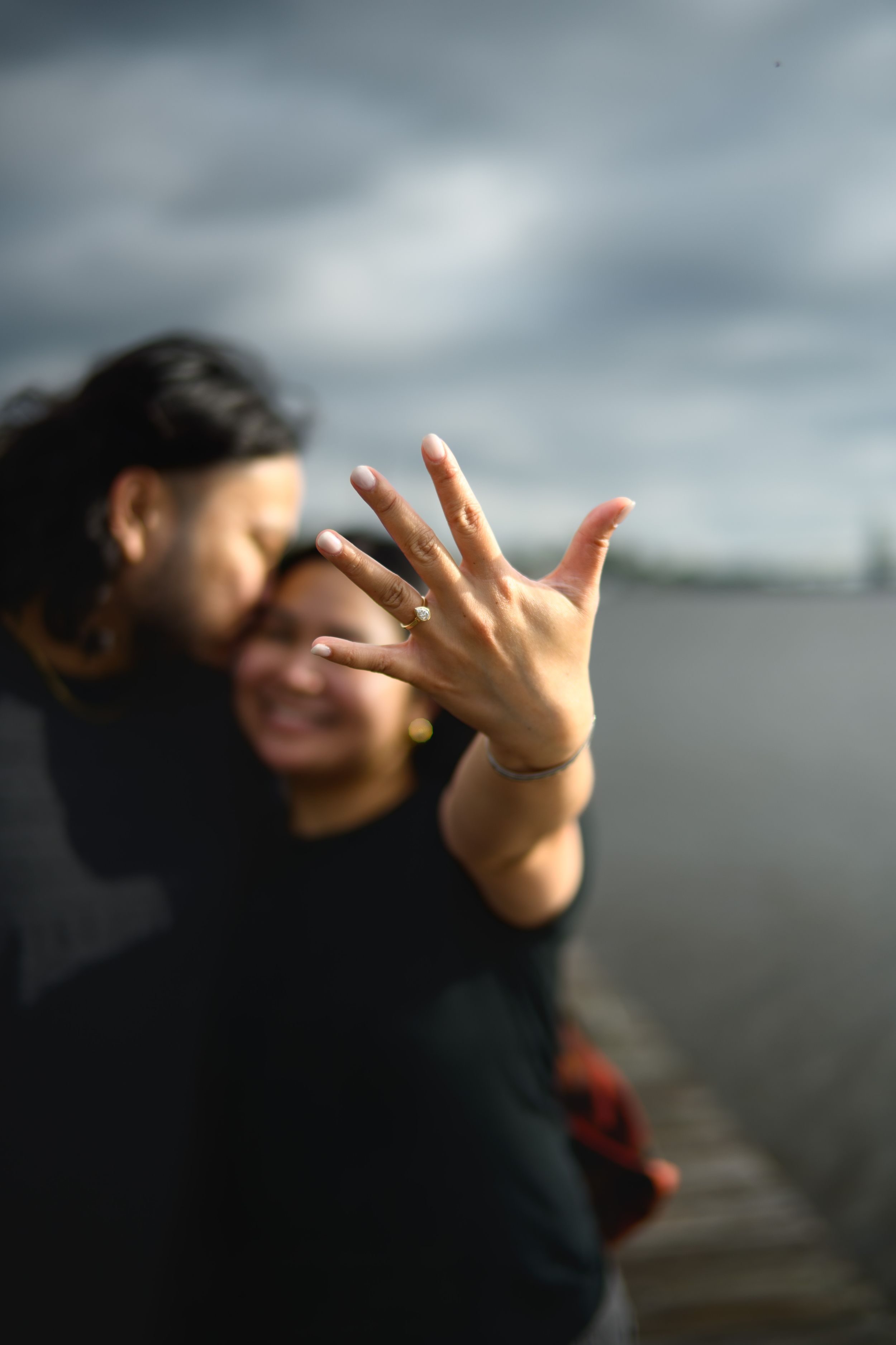 A sequence of hand gestures showing a ring against a moody cloudy sky background.