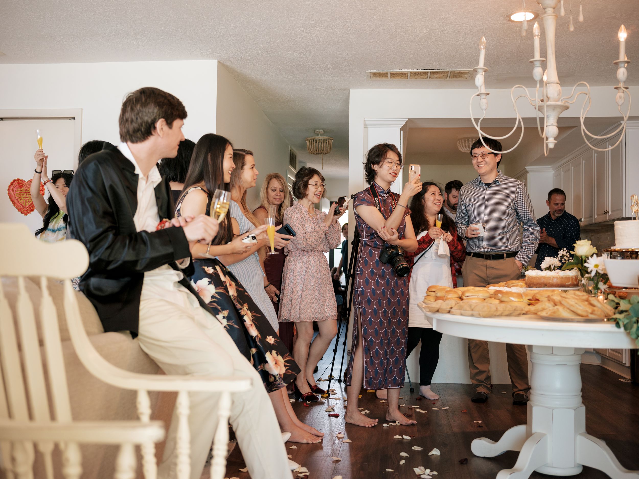 Guests mingling and enjoying food at an elegant indoor reception with white decor.