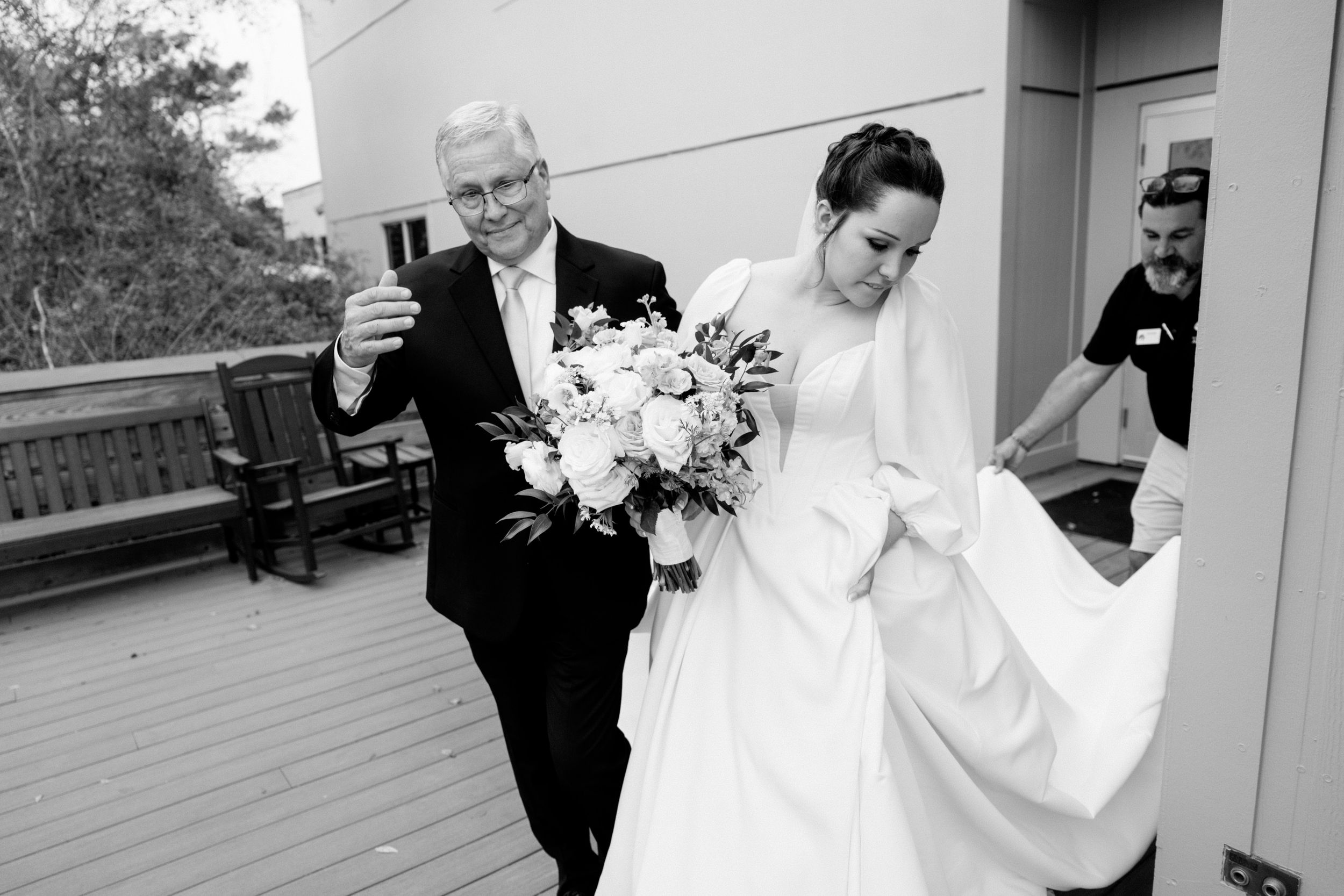 Wedding party members interact on a covered outdoor patio during celebration.