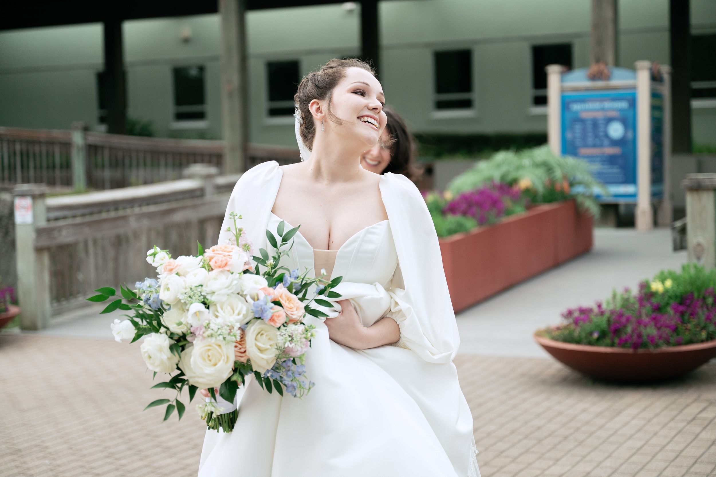 Elegant white wedding bouquet with roses and greenery against a white dress.