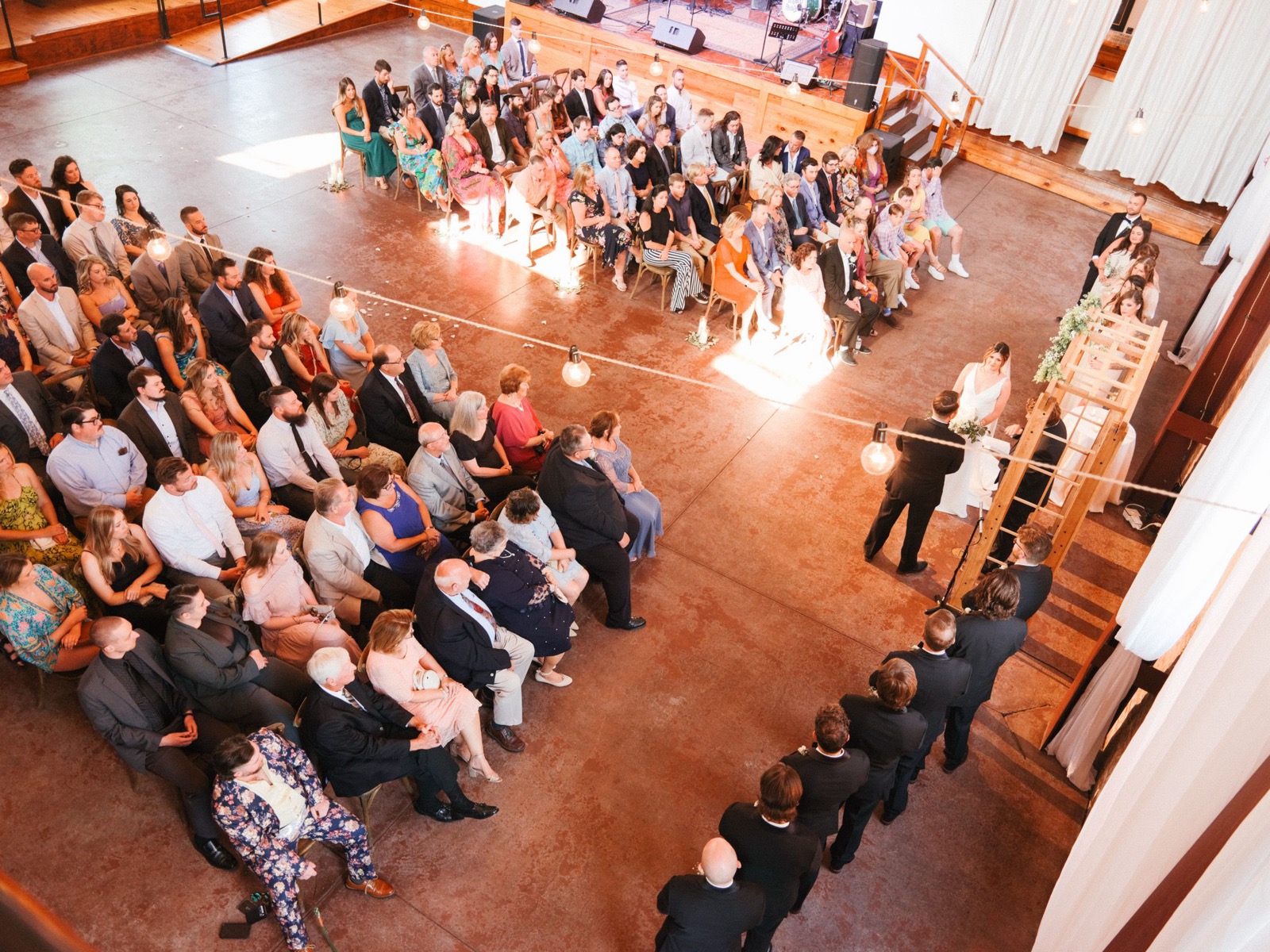 Elevated view of a wedding ceremony in progress with guests seated in rows facing the altar.