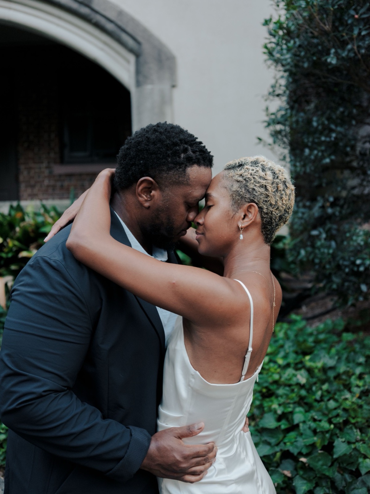 A romantic wedding moment captured in a garden setting with a couple sharing an intimate embrace.