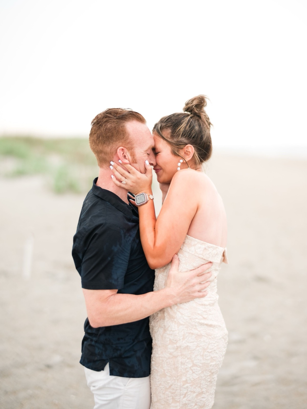 A tender moment between a couple sharing a kiss on the beach.