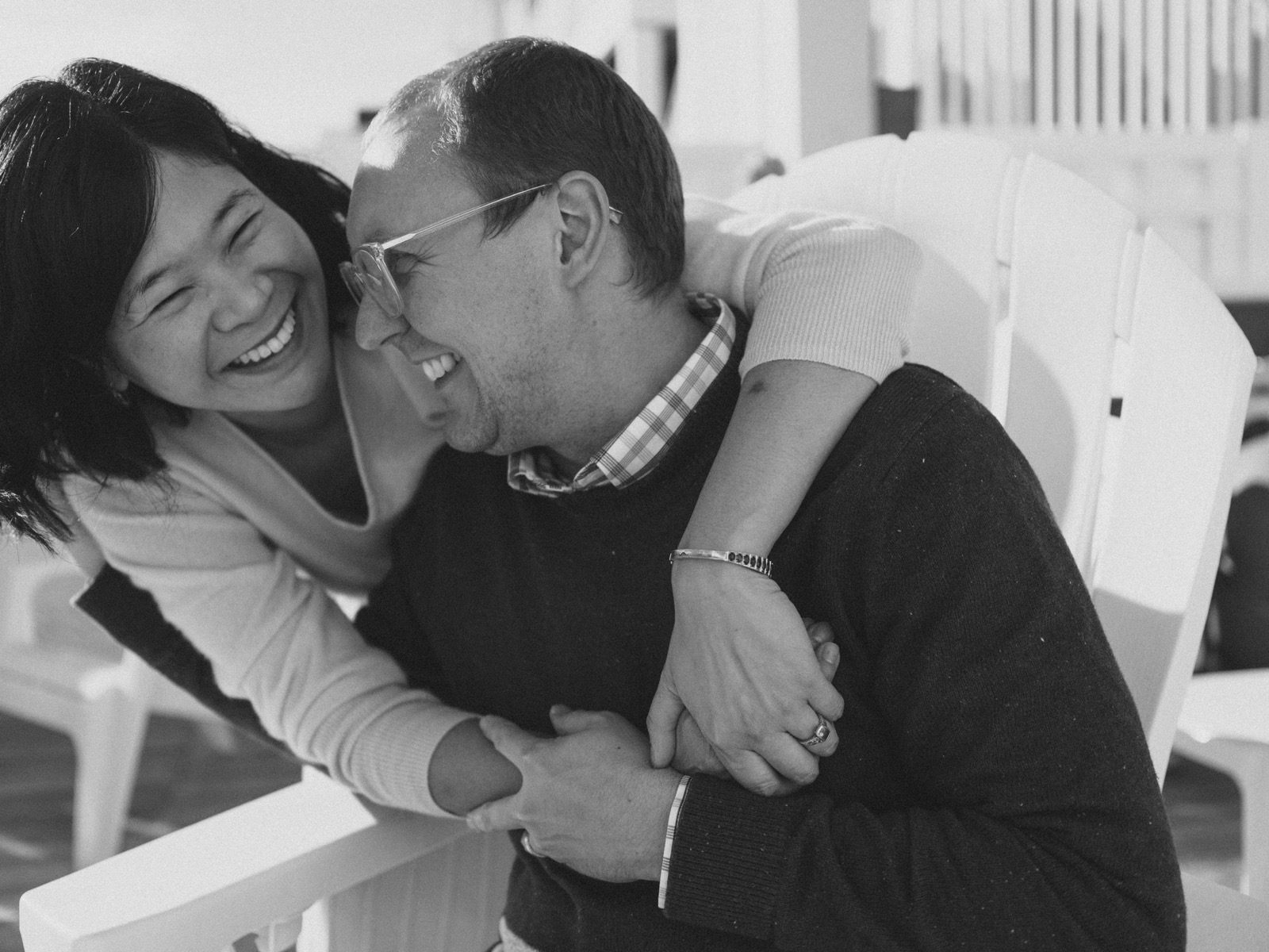 A black and white candid photo showing a couple sharing a joyful laugh together.