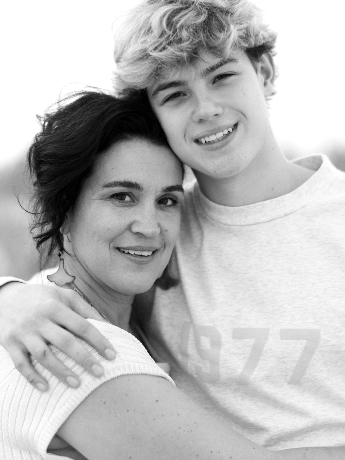 A black and white portrait of two people embracing and smiling warmly at the camera.