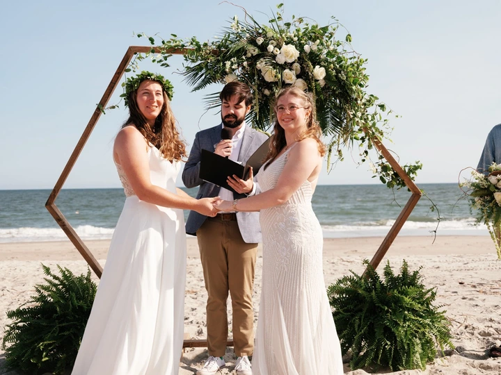 Couple beneath a floral geometric arch during their Shell Island beach ceremony