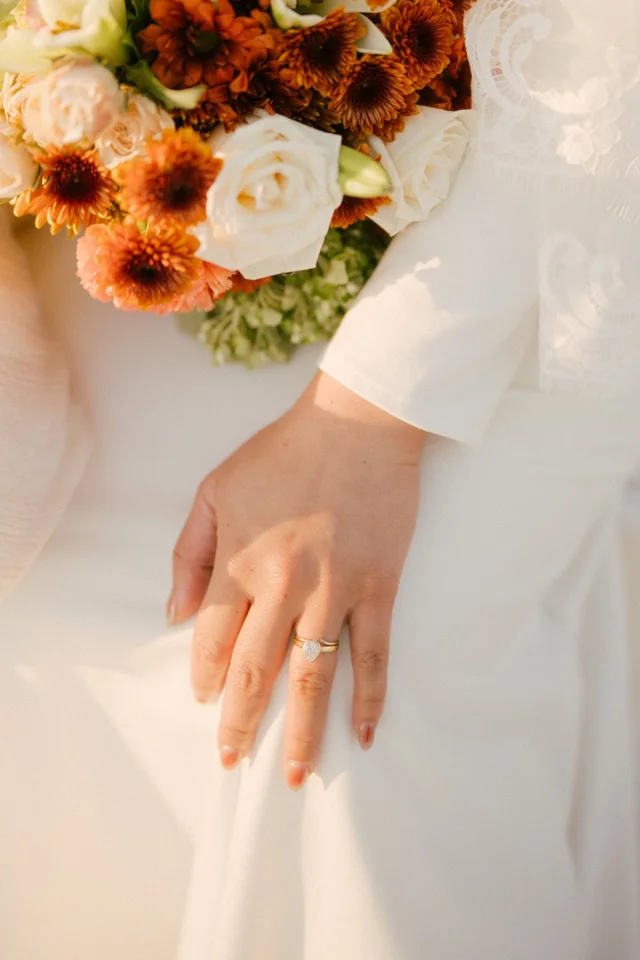 A bridal bouquet with colorful flowers beside a wedding dress