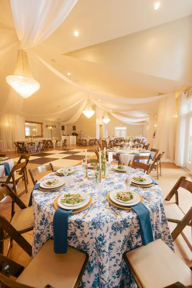A wedding reception room with arranged tables and floral centerpieces