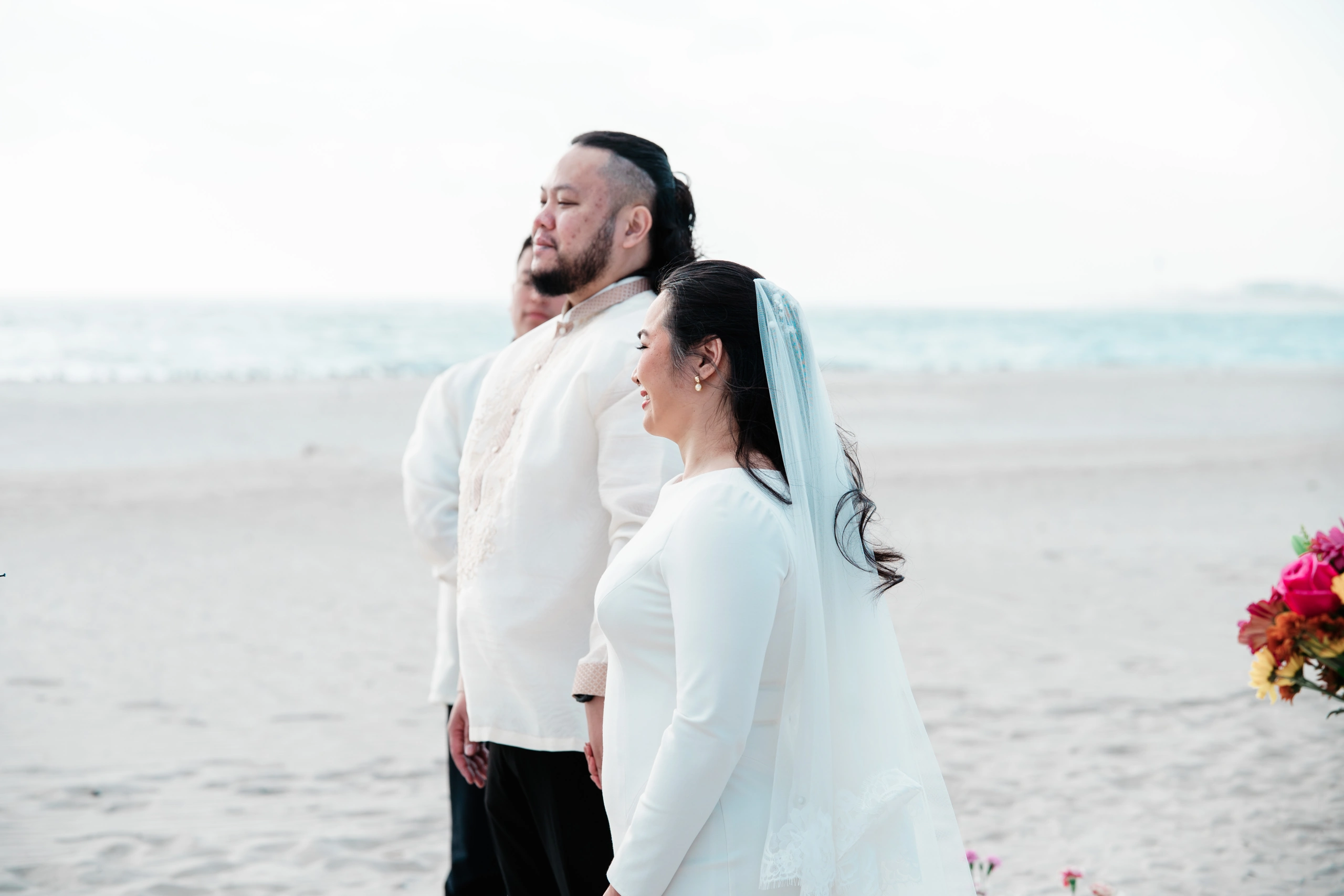 Portrait of a young person in a white dress smiling at the beach.