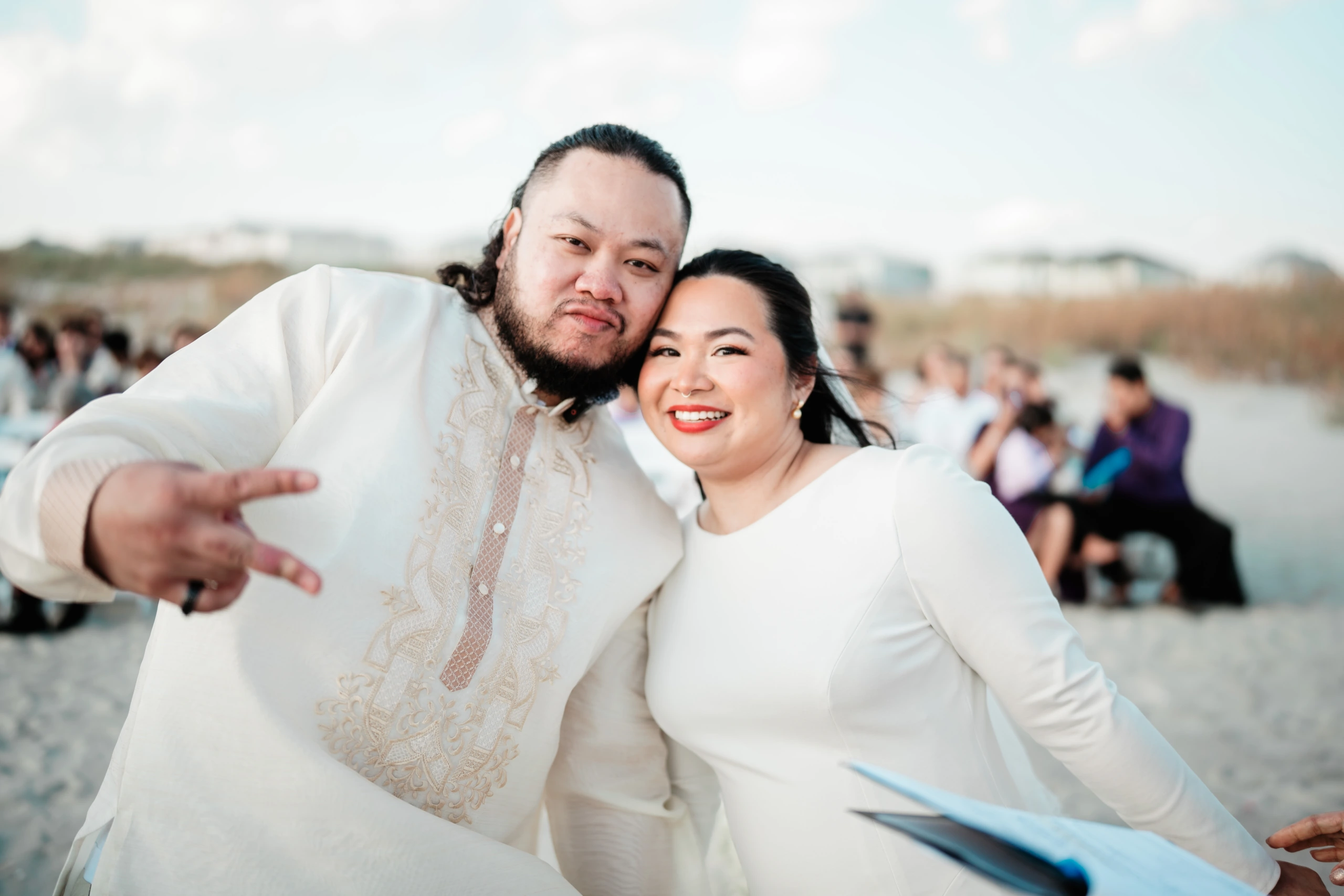 Extended family group photo on the beach with cloudy sky backdrop.