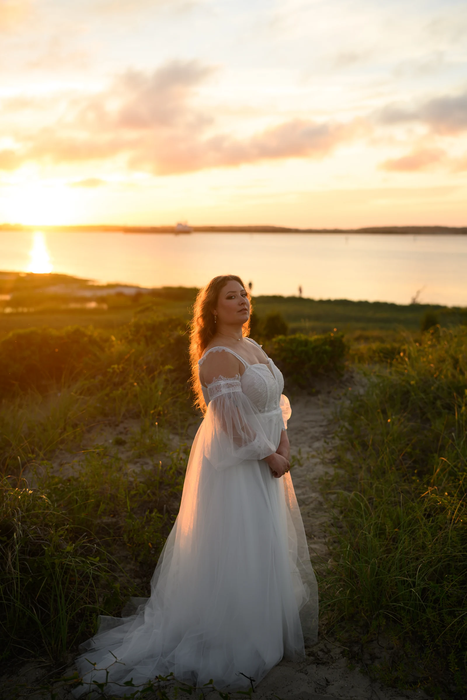 A sunset portrait in a white dress beside the water.
